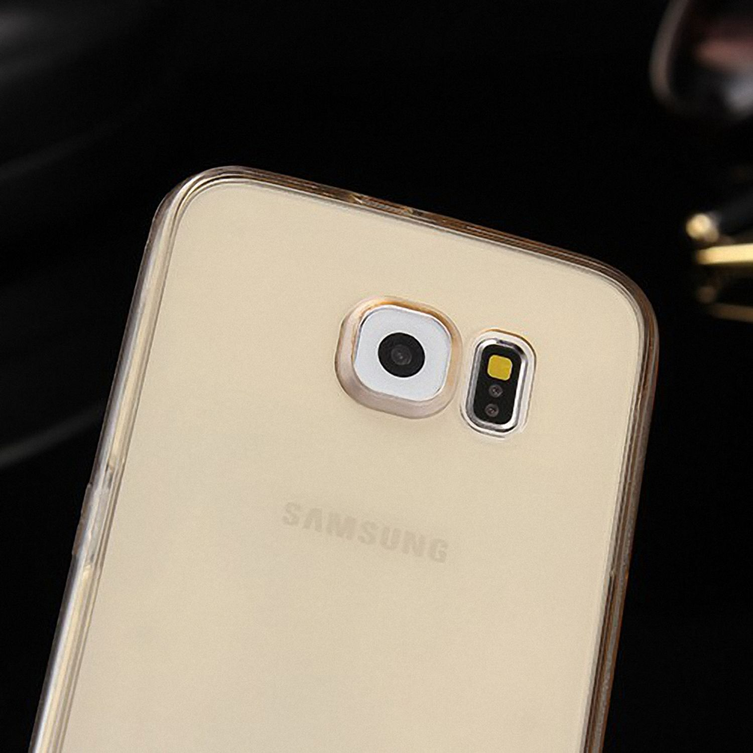 Nahaufnahme einer Handyhülle mit einem Kameraobjektiv. Die Hülle ist transparent mit Goldtönung.