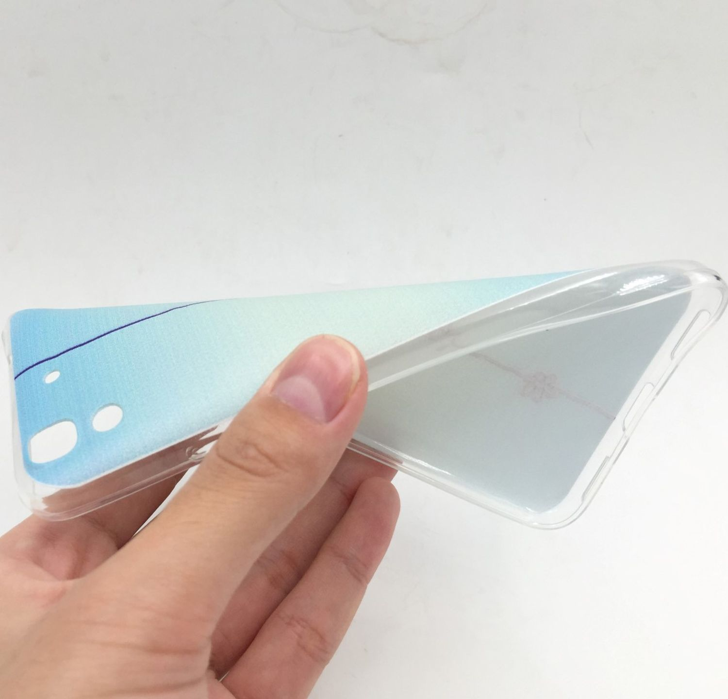 Eine klare Handyhülle, Hand, die die Hülle hält. Die Hülle hat ein blaues und weißes Design.