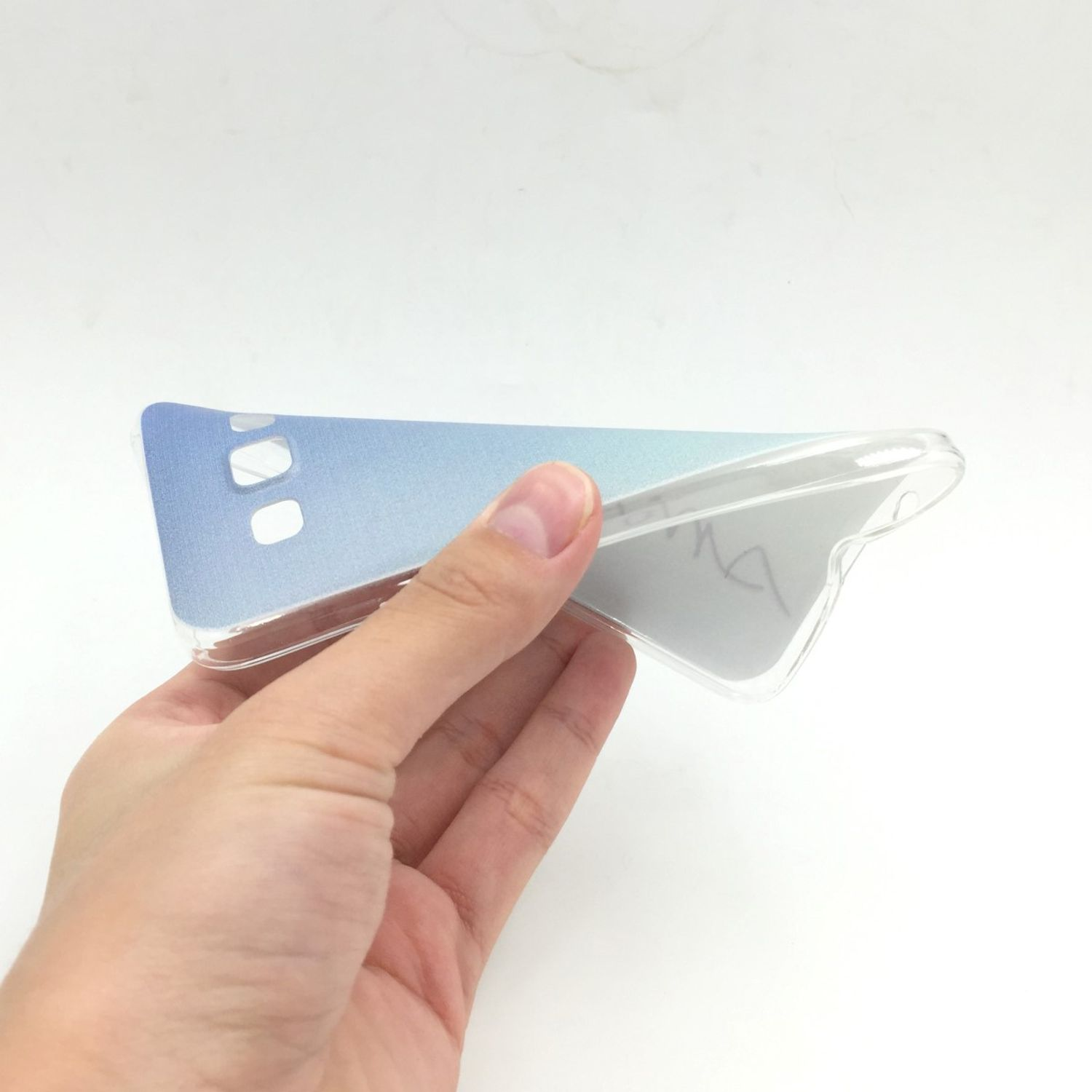 Hand hält eine Handyhülle. Transparente Kunststoffhülle mit blauem Farbverlauf. Weißer Hintergrund.
