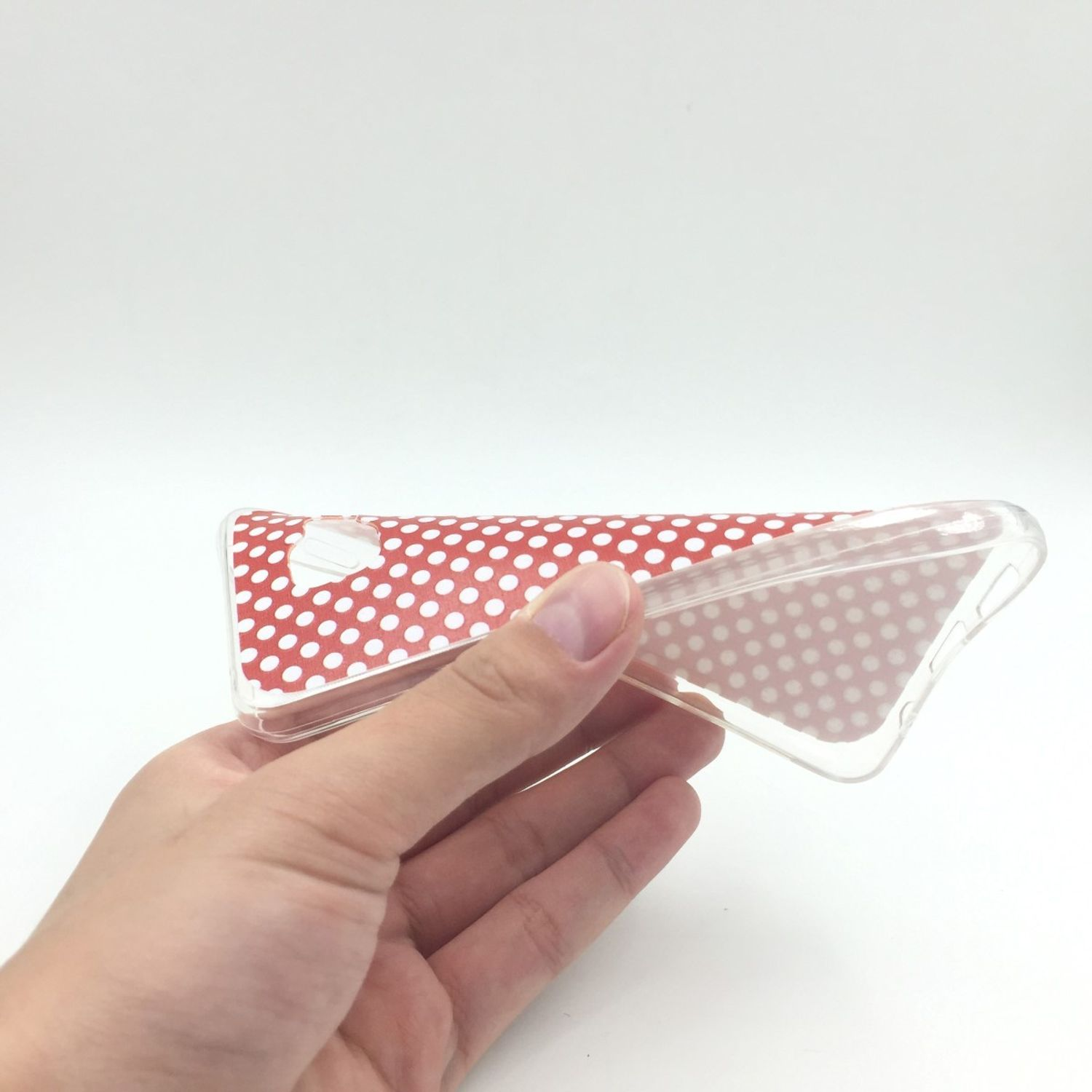 Hand hält transparente Handyhülle mit roten Punkten auf weißem Hintergrund.