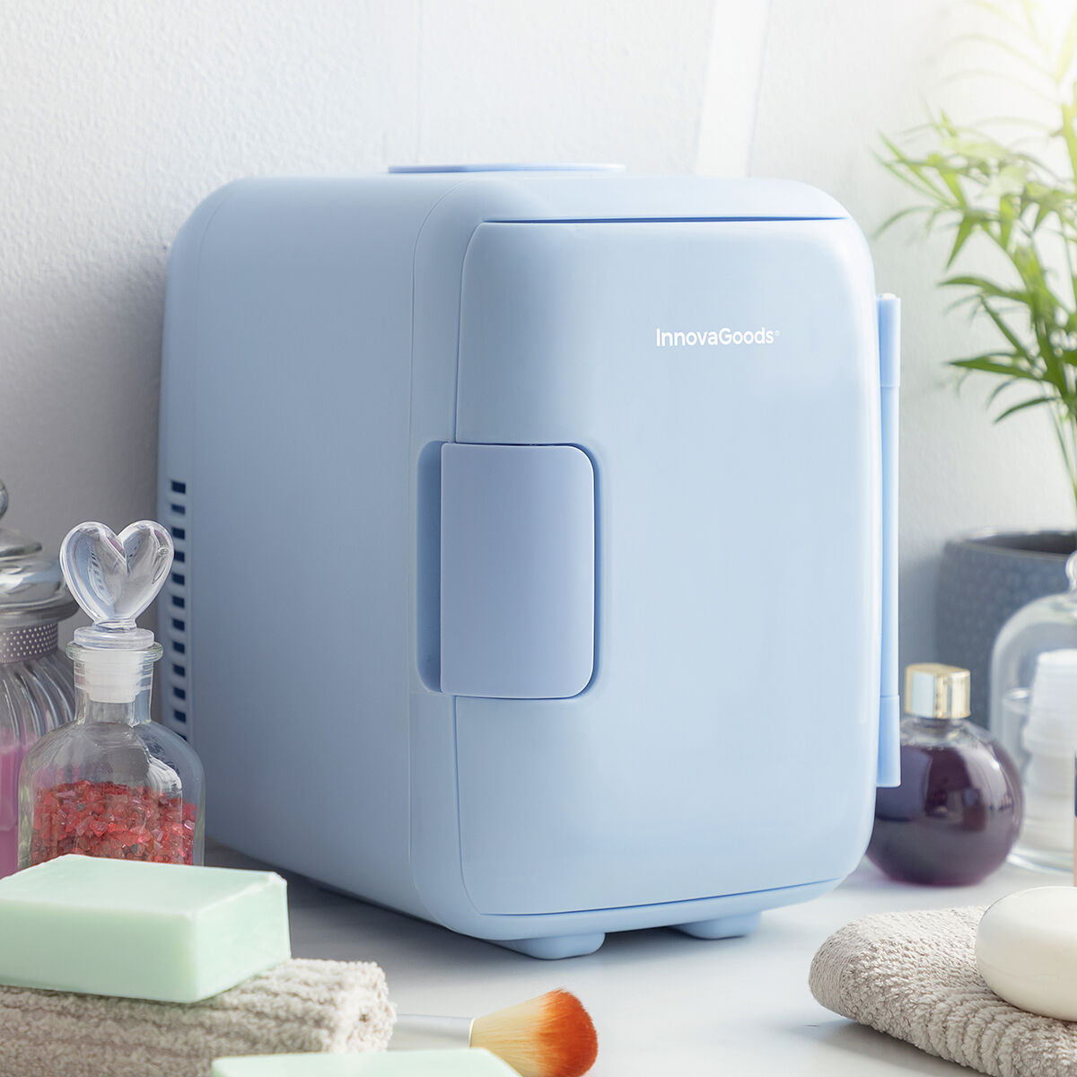 Una mini nevera InnovaGoods azul claro sobre una superficie con productos de belleza.