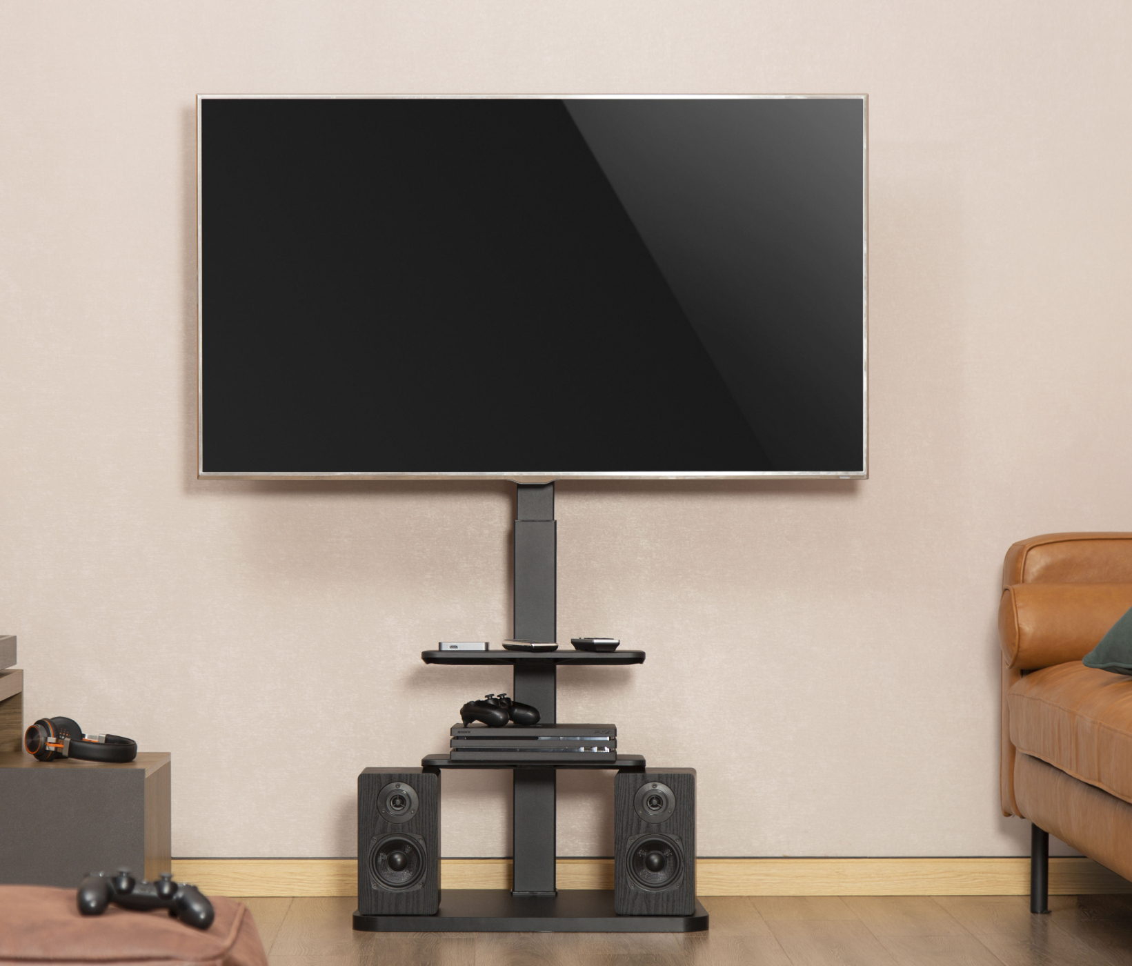Fernseher auf schwarzem Ständer. Lautsprecher und Konsole darunter. Braunes Sofa rechts.