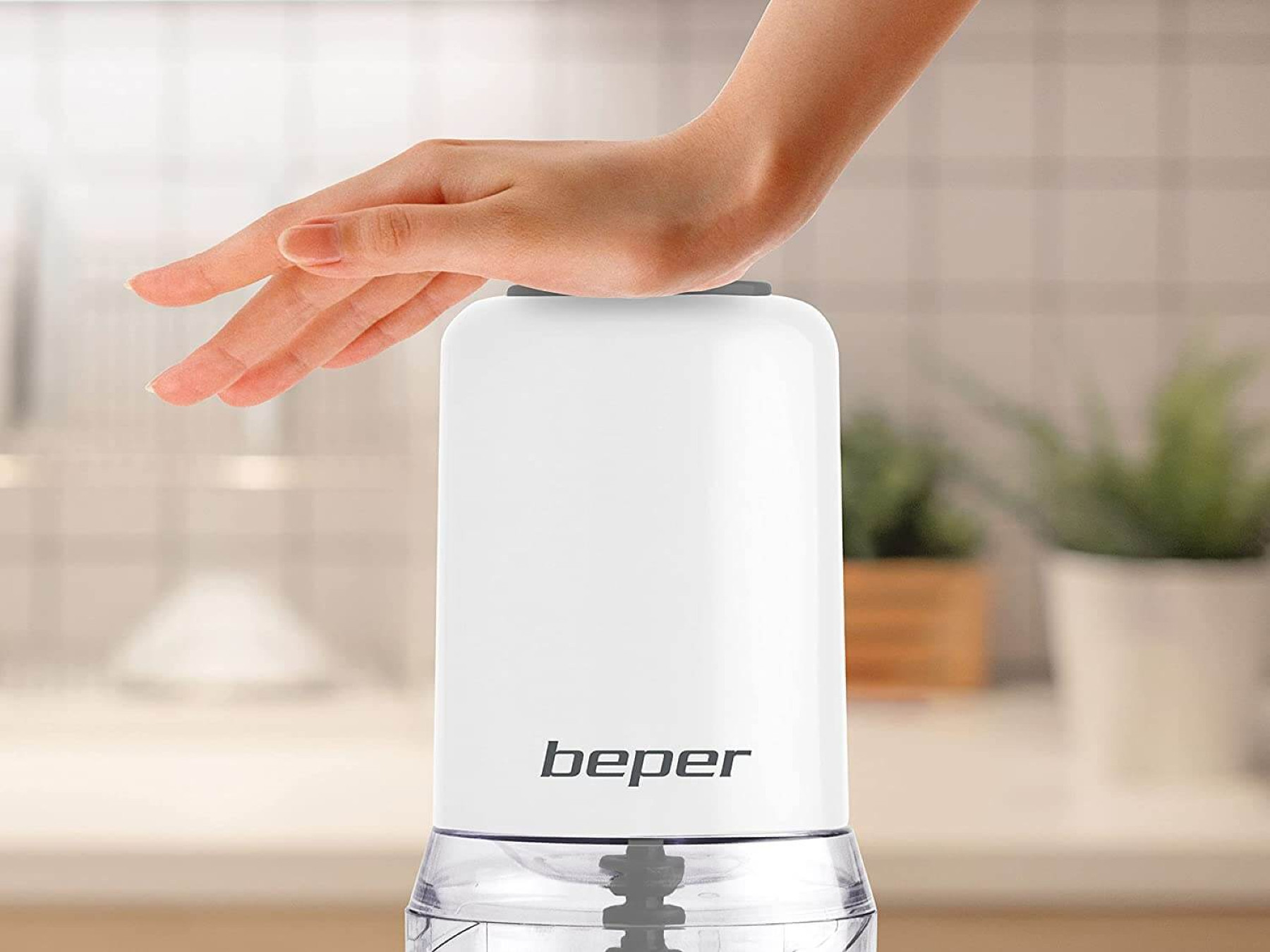 Un robot da cucina bianco con la mano di una persona sopra.