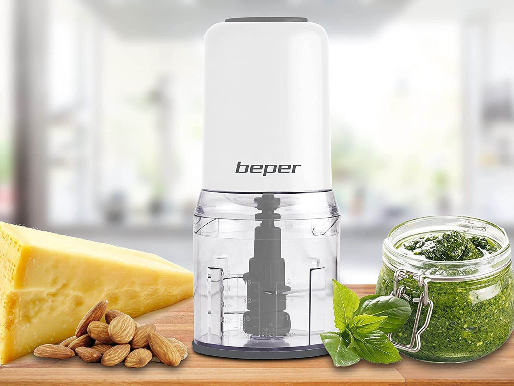 Un mini chopper Beper bianco con un contenitore trasparente. Ci sono pesto, formaggio e mandorle nella scena.