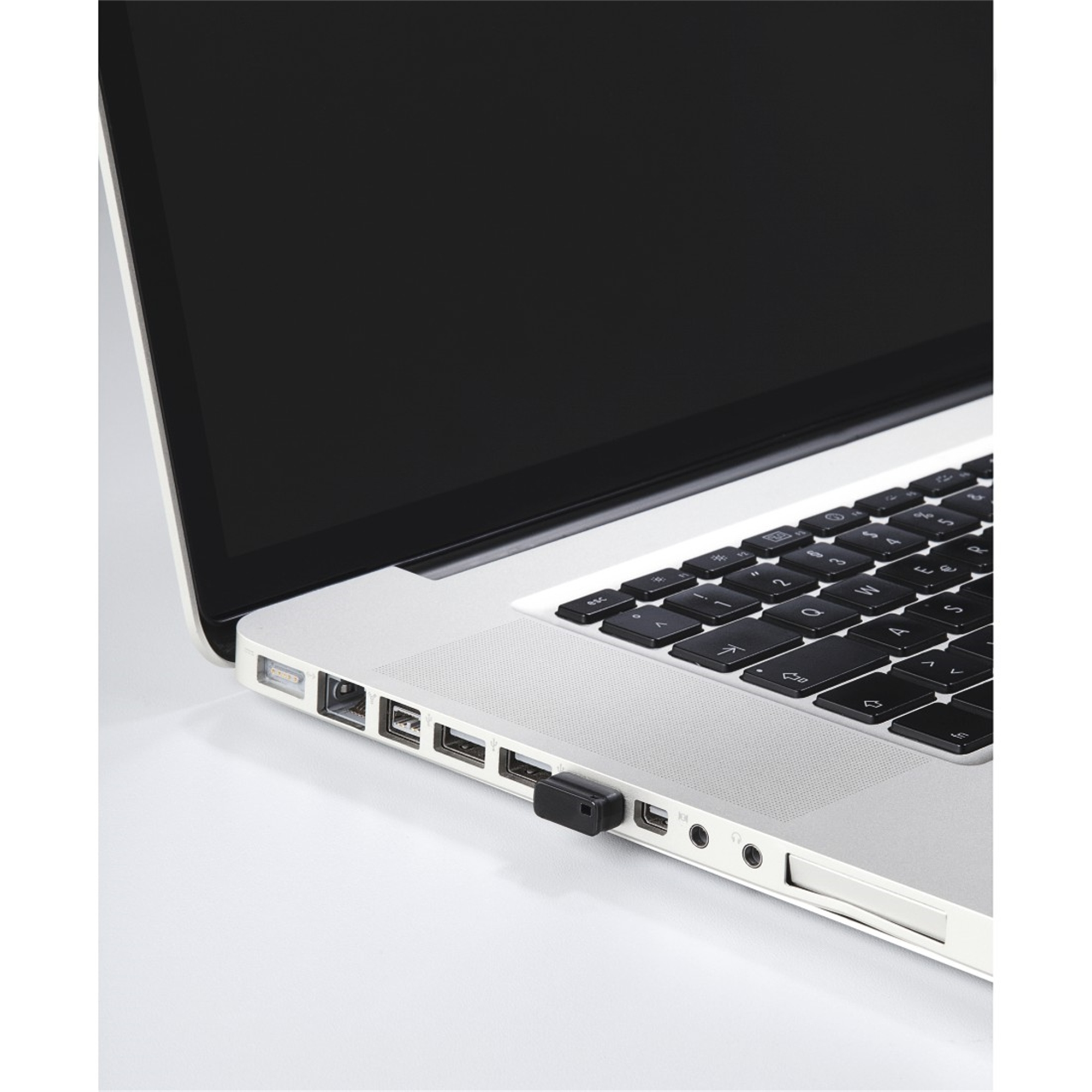 Laptop z podłączonym czarnym adapterem USB. Zbliżenie na bok laptopa.