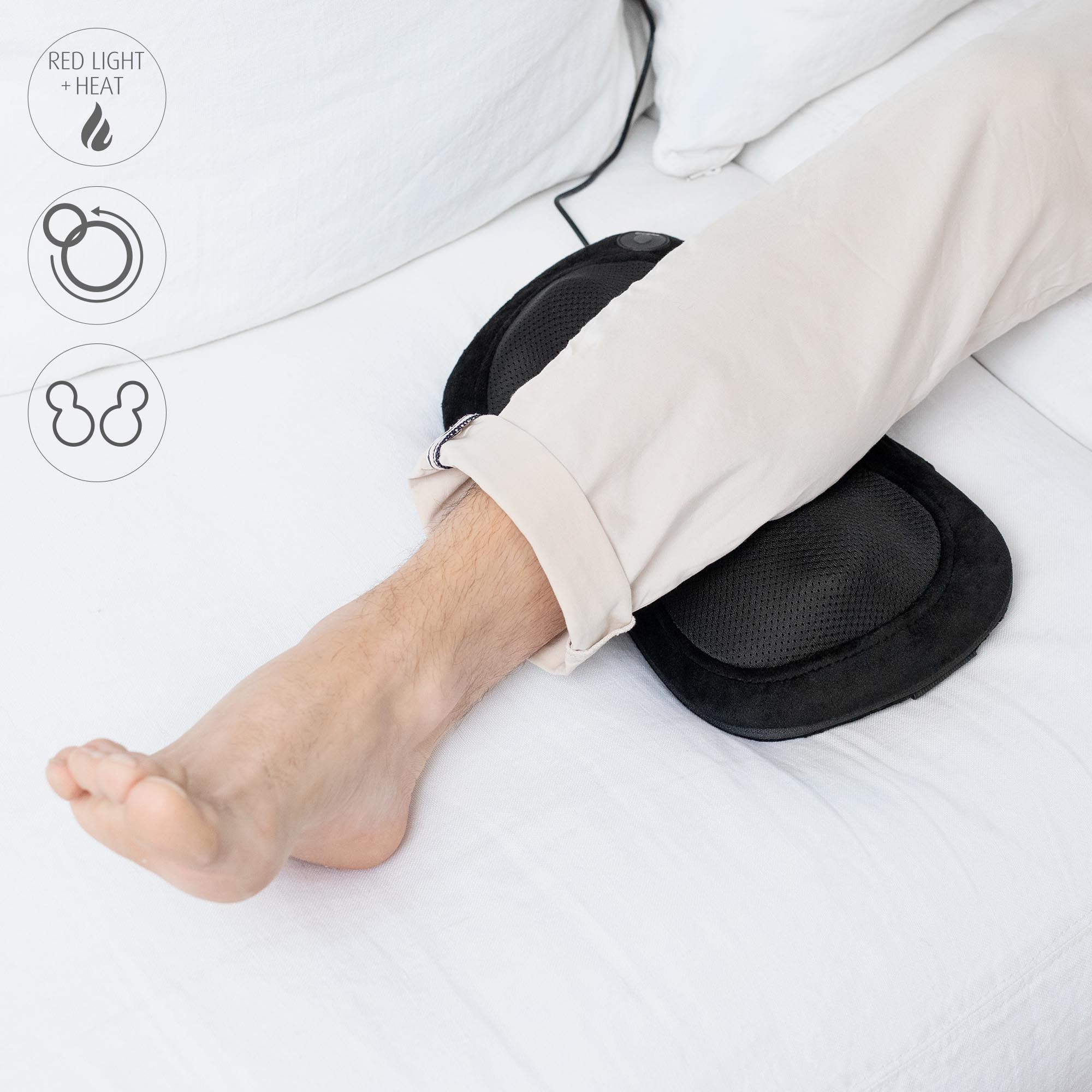 Ein Bein eines Mannes auf einem Bett, mit einem schwarzen Massagegerät, neben Symbolen.