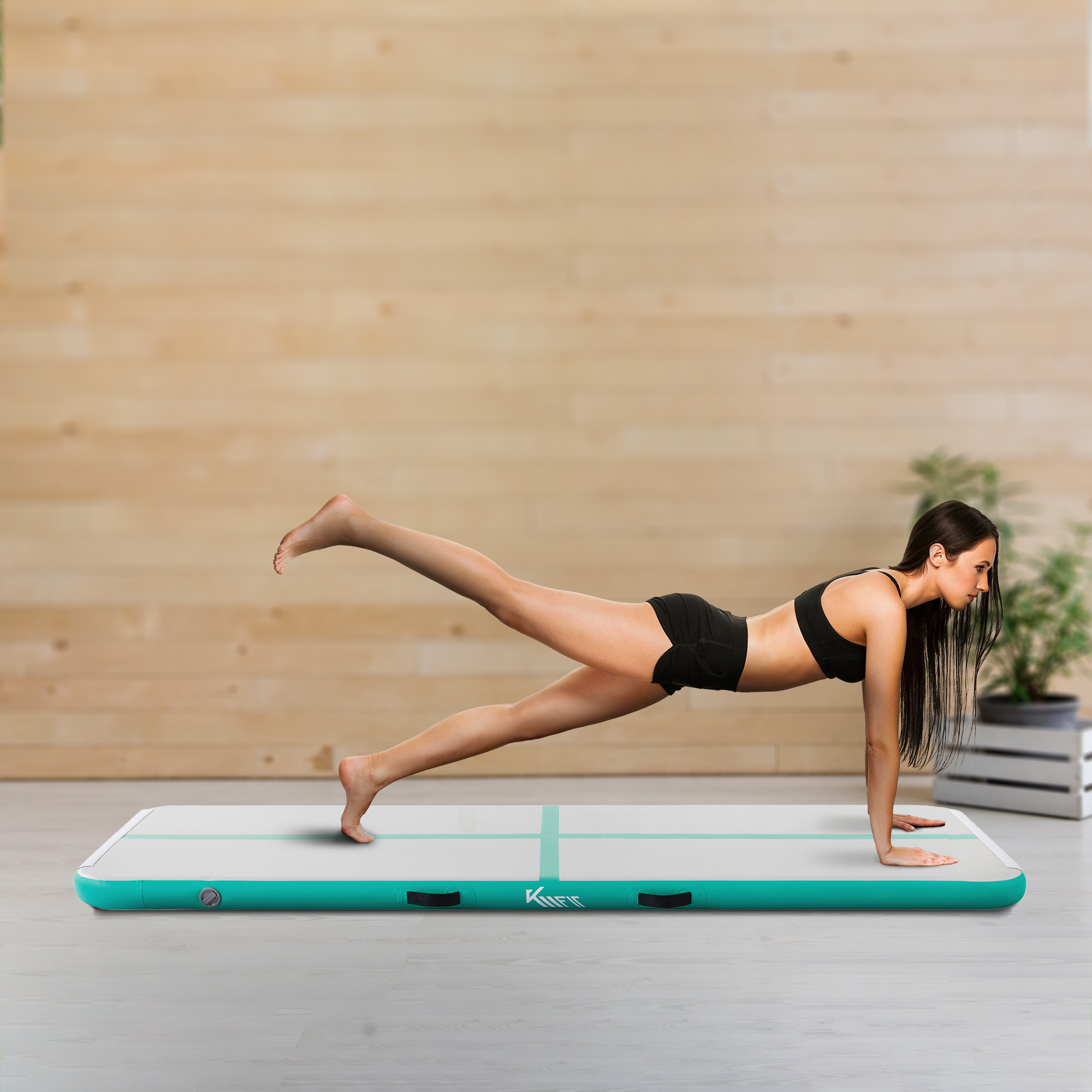 Eine Frau macht eine Plank auf einer türkis-weißen Matte. Der Hintergrund ist eine Holzwand und eine Pflanze.