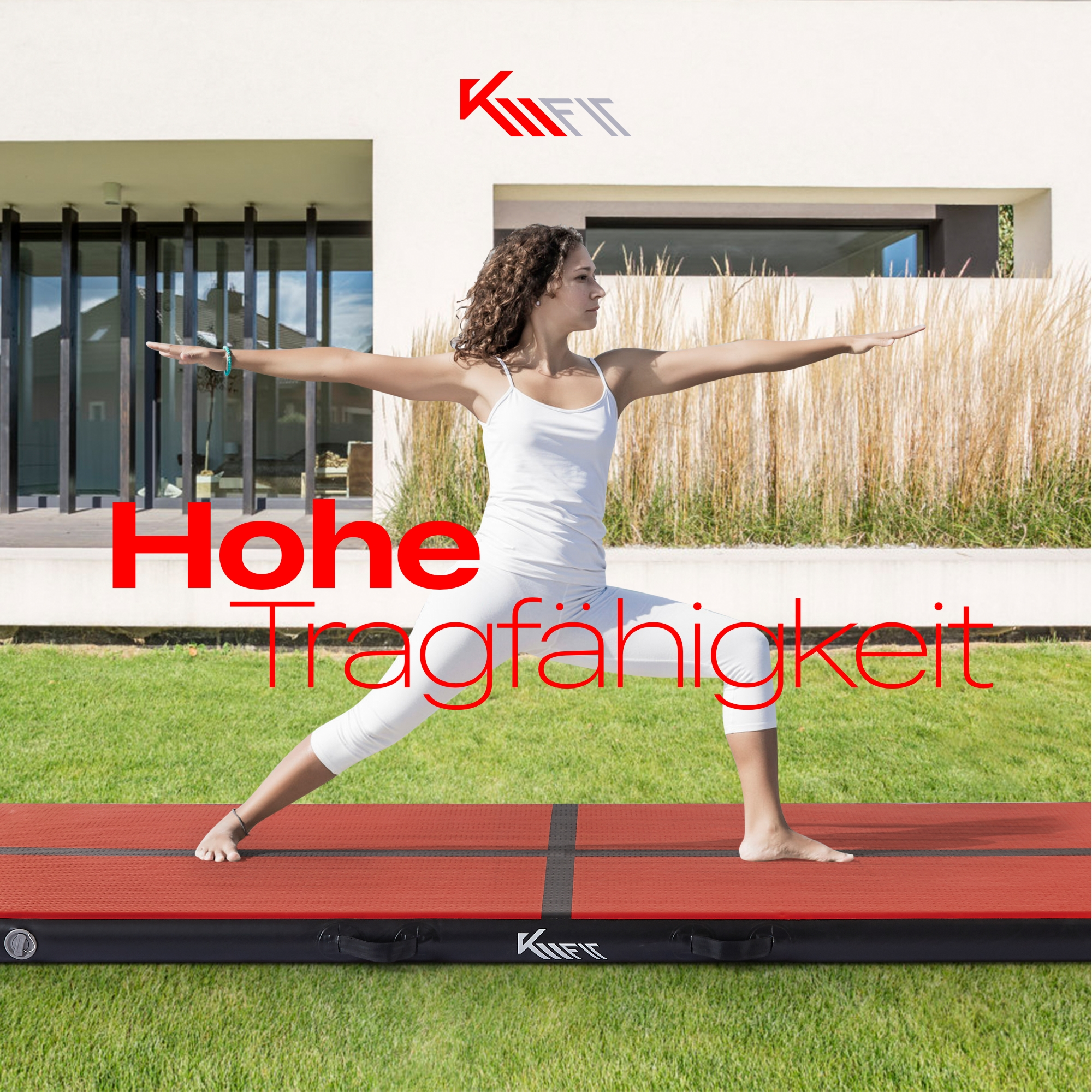 Frau in Yogapose auf roter Matte auf Rasen, mit Gebäude im Hintergrund.
