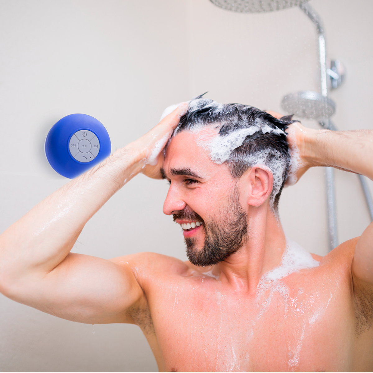 Hombre duchándose, lavando cabello. Altavoz azul impermeable a la izquierda. Sonriendo.