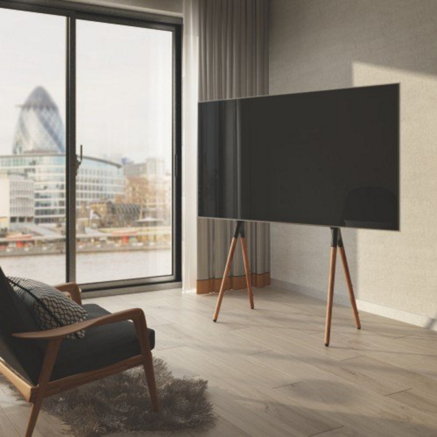 Woonkamer met tv op houten standaard, uitzicht op de stad vanuit het raam, fauteuil en vloerkleed.