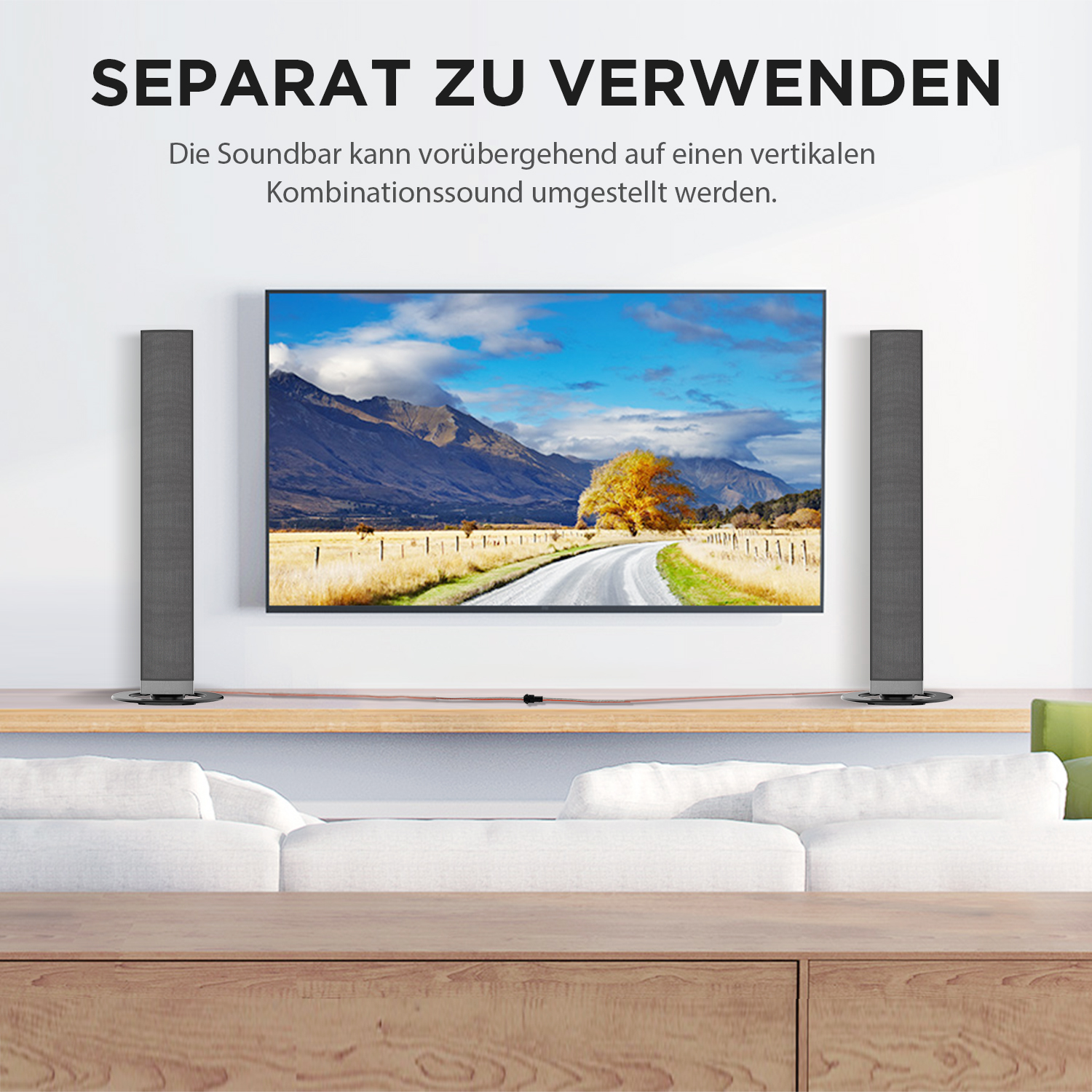 Fernseher mit Lautsprechern auf jeder Seite. Hintergrund zeigt Landschaft mit Straße und Bäumen.