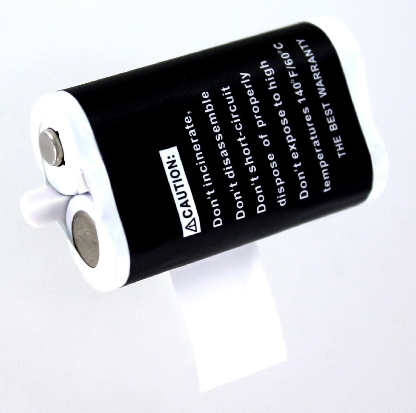 Zwei zylindrische Batterien, schwarz-weißes Etikett mit Warnhinweisen, auf Oberfläche.