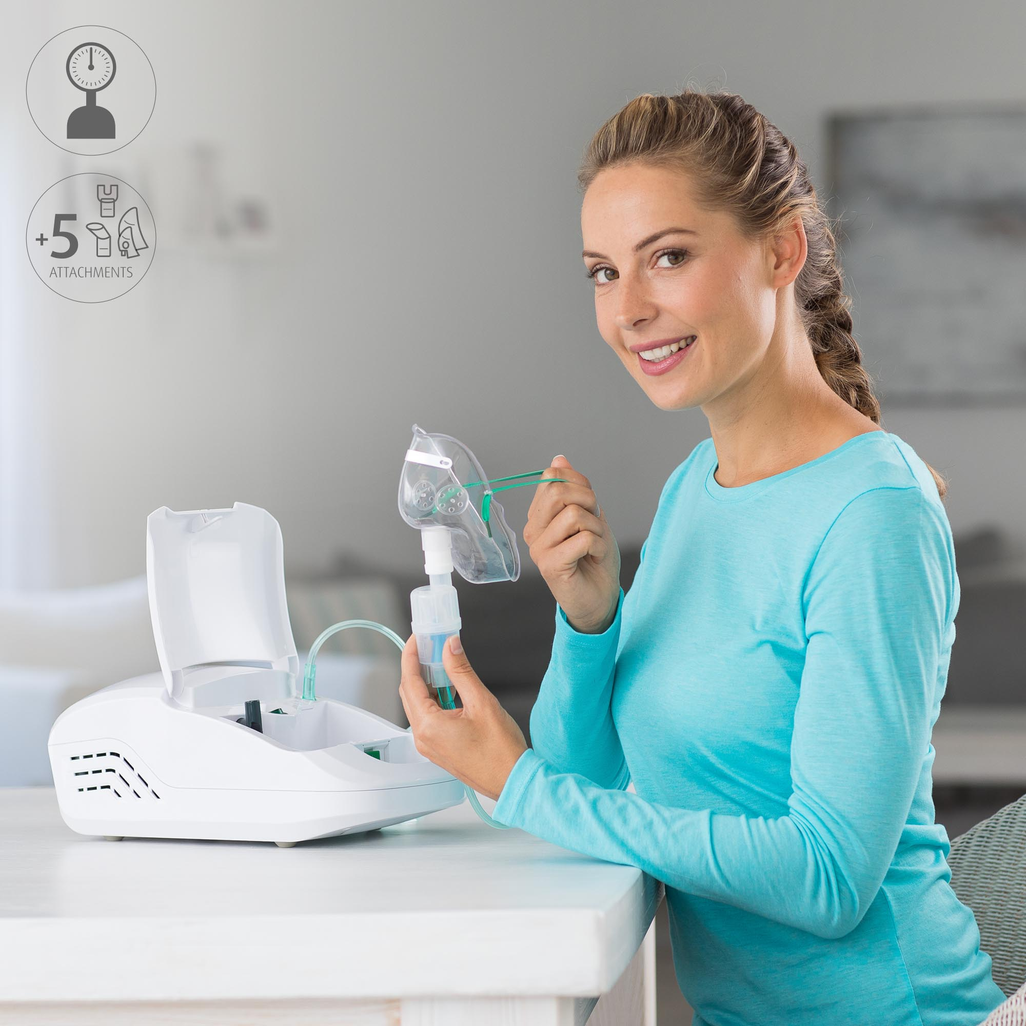 Eine Frau hält eine Verneblermaske. Eine Verneblermaschine steht auf einem Tisch. Sie lächelt und schaut in die Kamera.