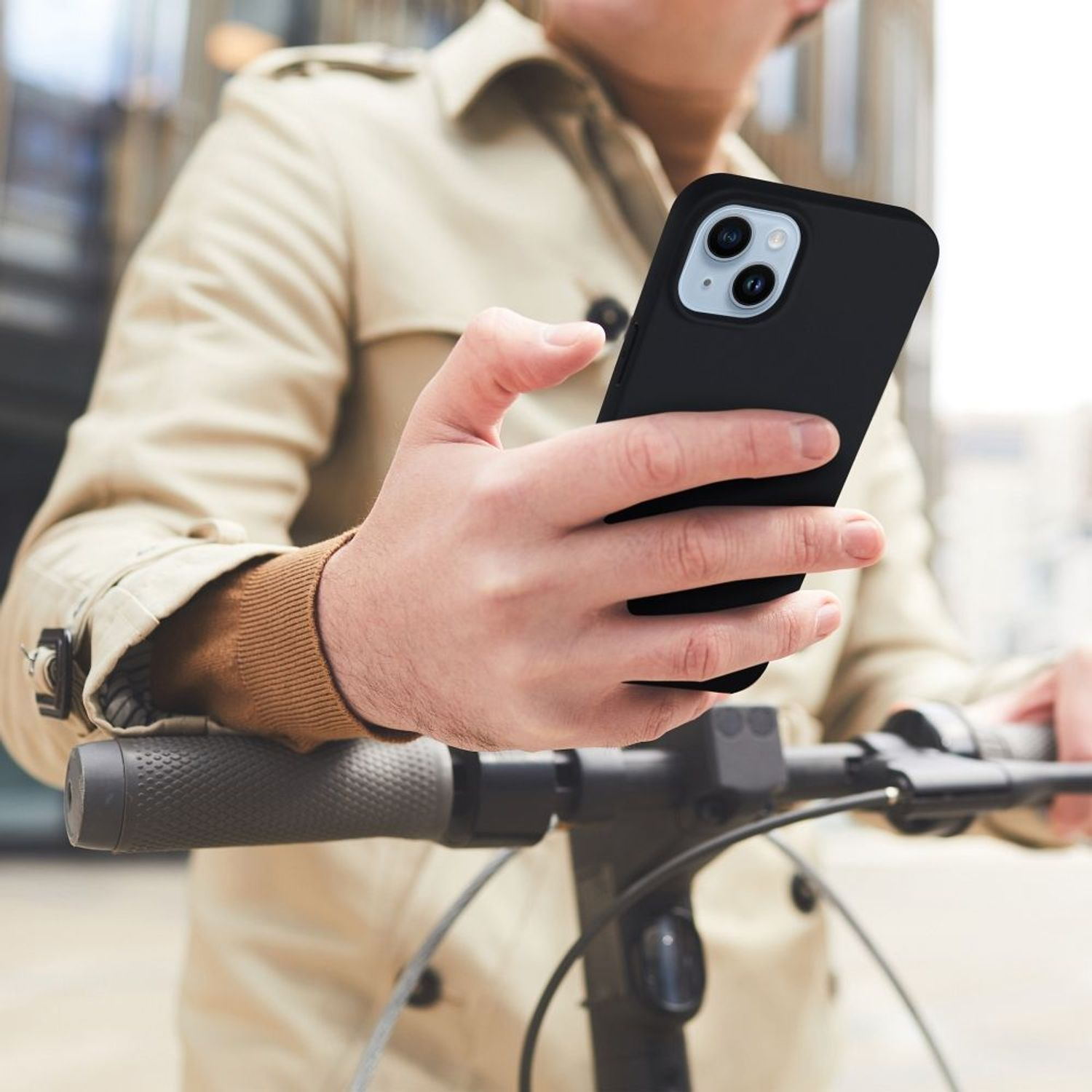 Eine Person auf einem Roller hält ein schwarzes Telefon mit moderner Kamera, verschwommener Hintergrund.