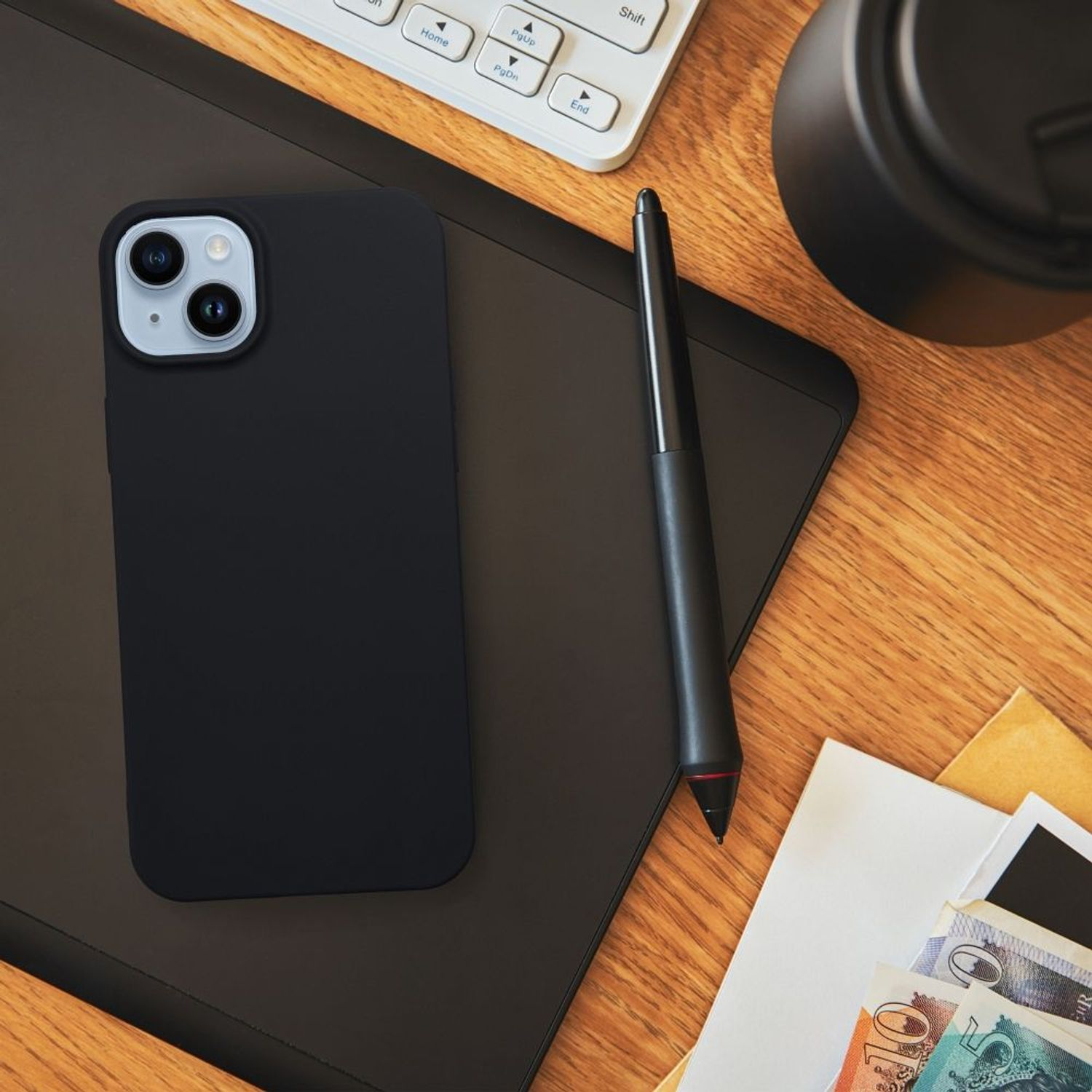 Schwarzes Telefon mit Hülle, auf dunkler Oberfläche mit Stift, Tastatur.
