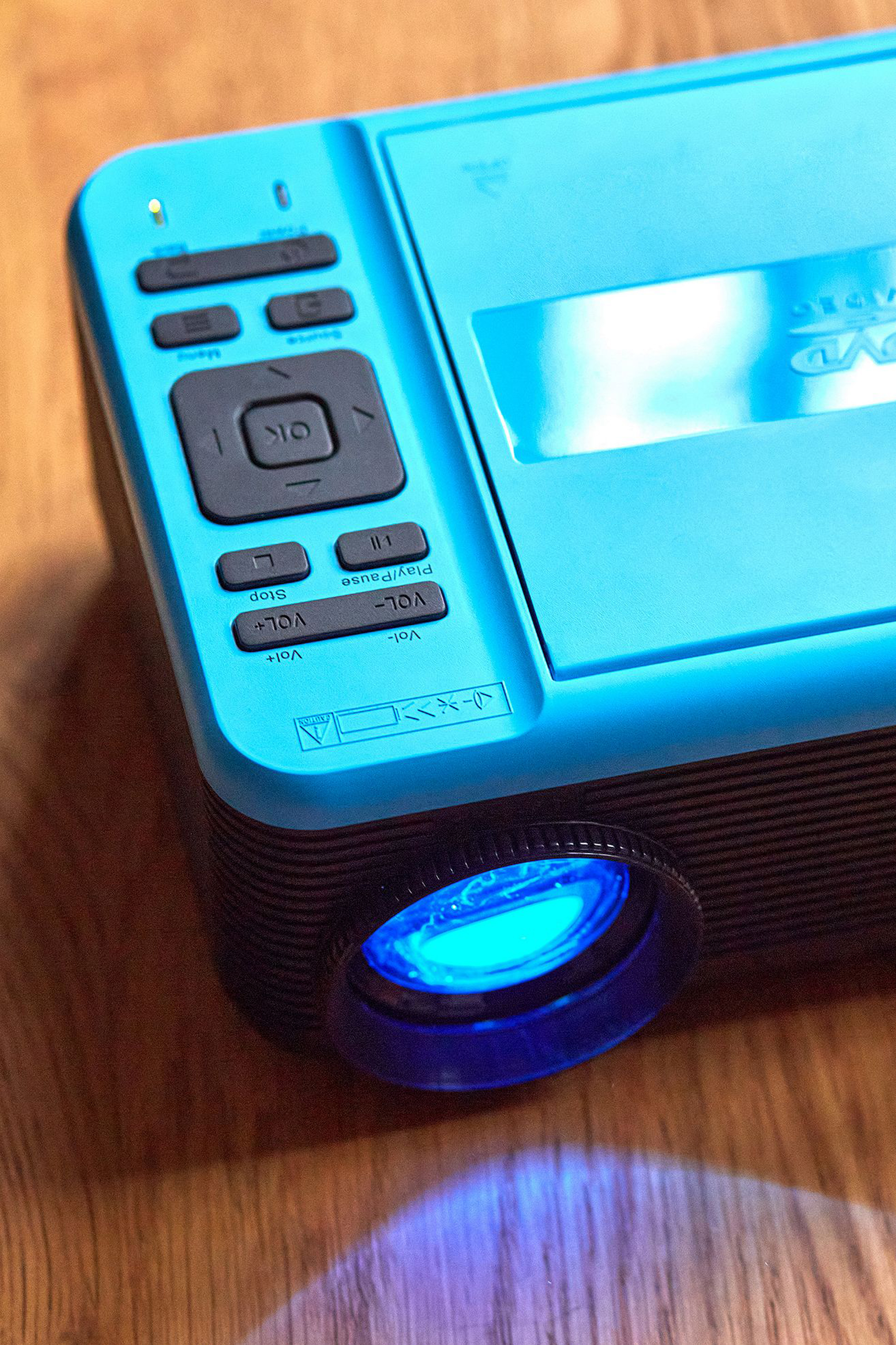 Zbliżenie niebieskiego odtwarzacza DVD z przyciskami i wiązką światła. Obiektyw jest niebieski.