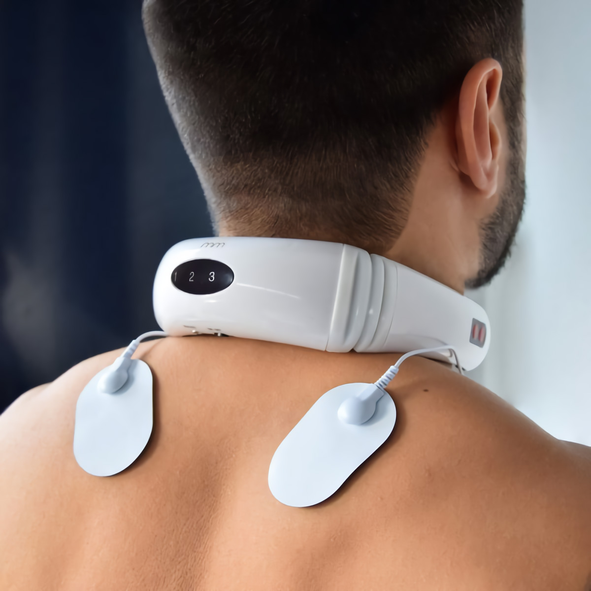 Espalda de hombre con masajeador de cuello blanco. Tres ajustes de botón, dos almohadillas conectadas.