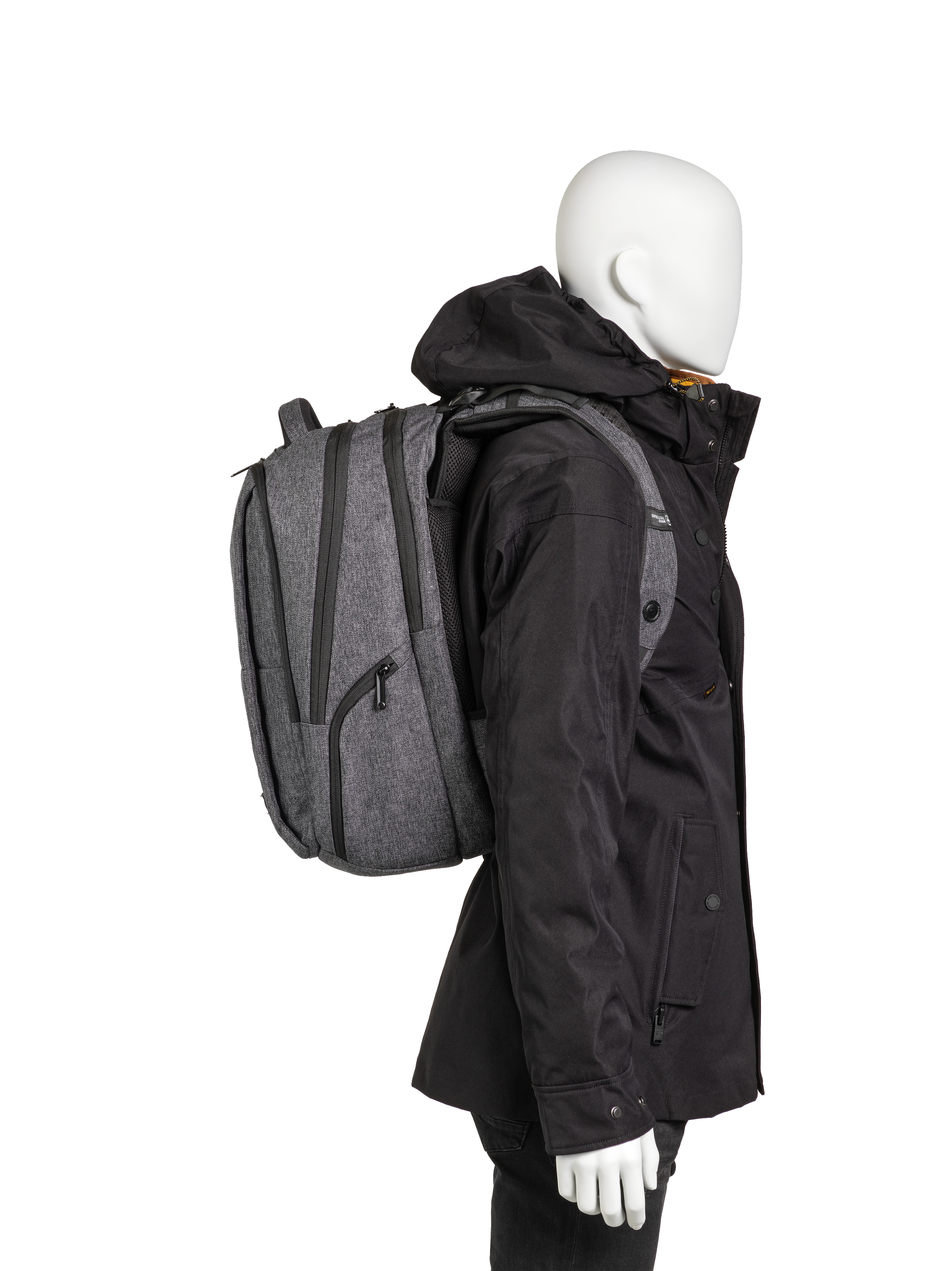 Eine Schaufensterpuppe mit Rucksack und schwarzer Jacke auf weißem Hintergrund.