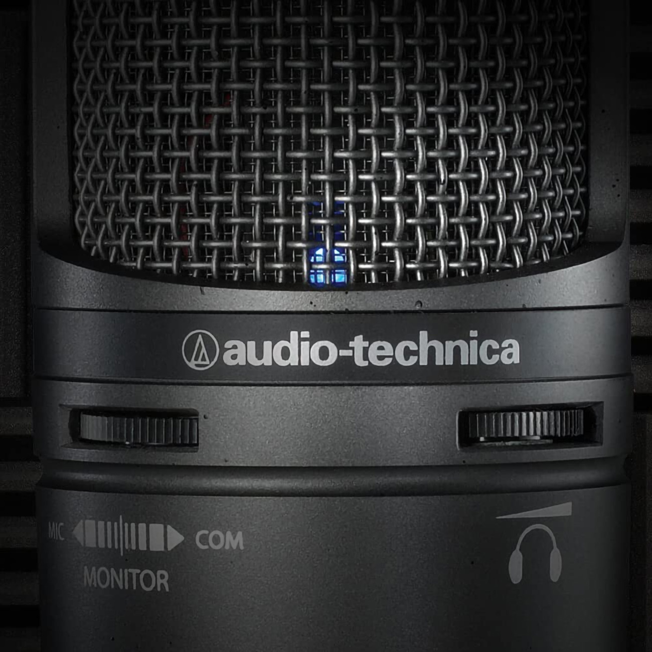 Ein schwarzes Audio-Technica-Mikrofon. Text auf dem Gehäuse. Metallischer Netzschutzkopf. Monitor- und Mikrofonregler.