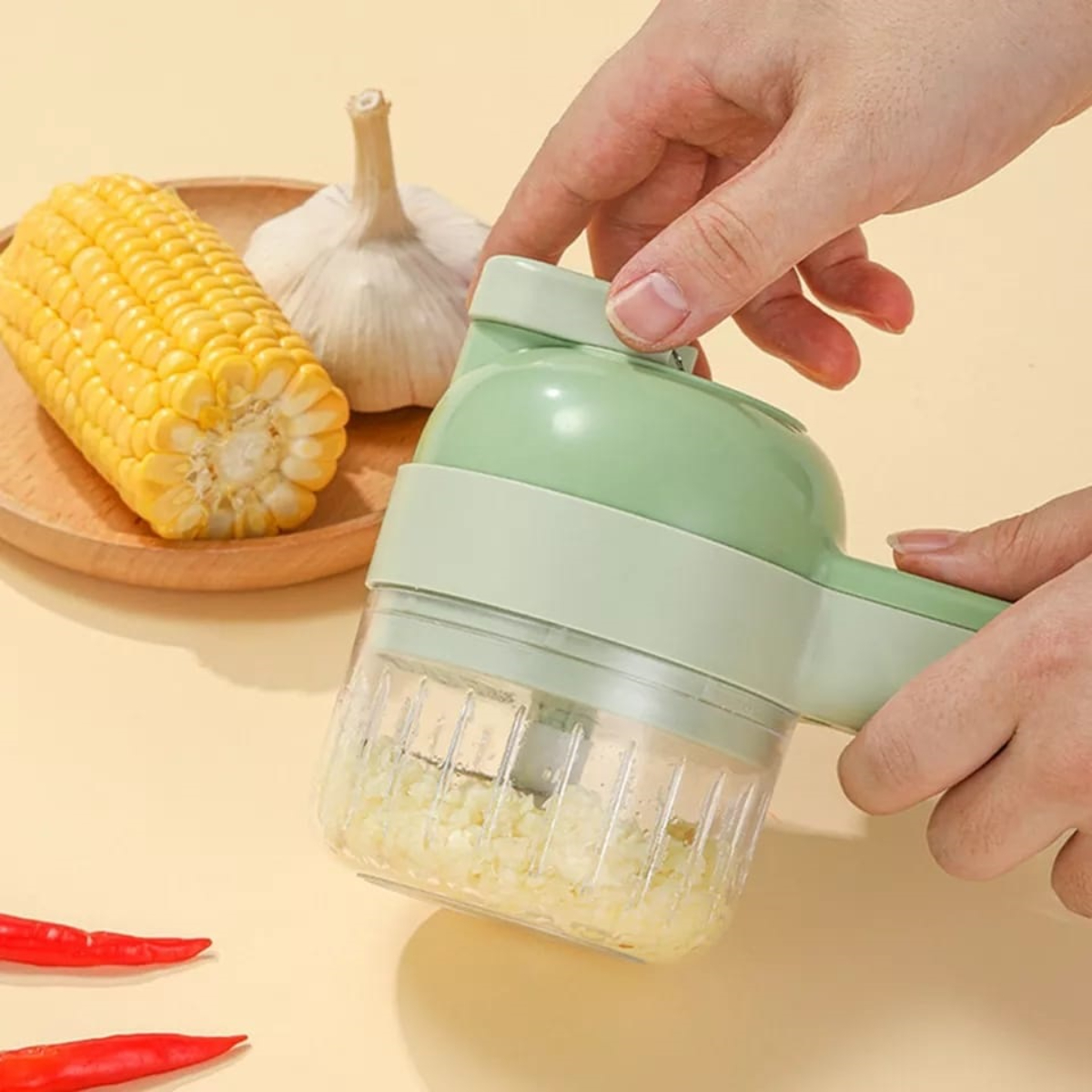 Picadora de alimentos verde y blanca con ajo picado en el recipiente.