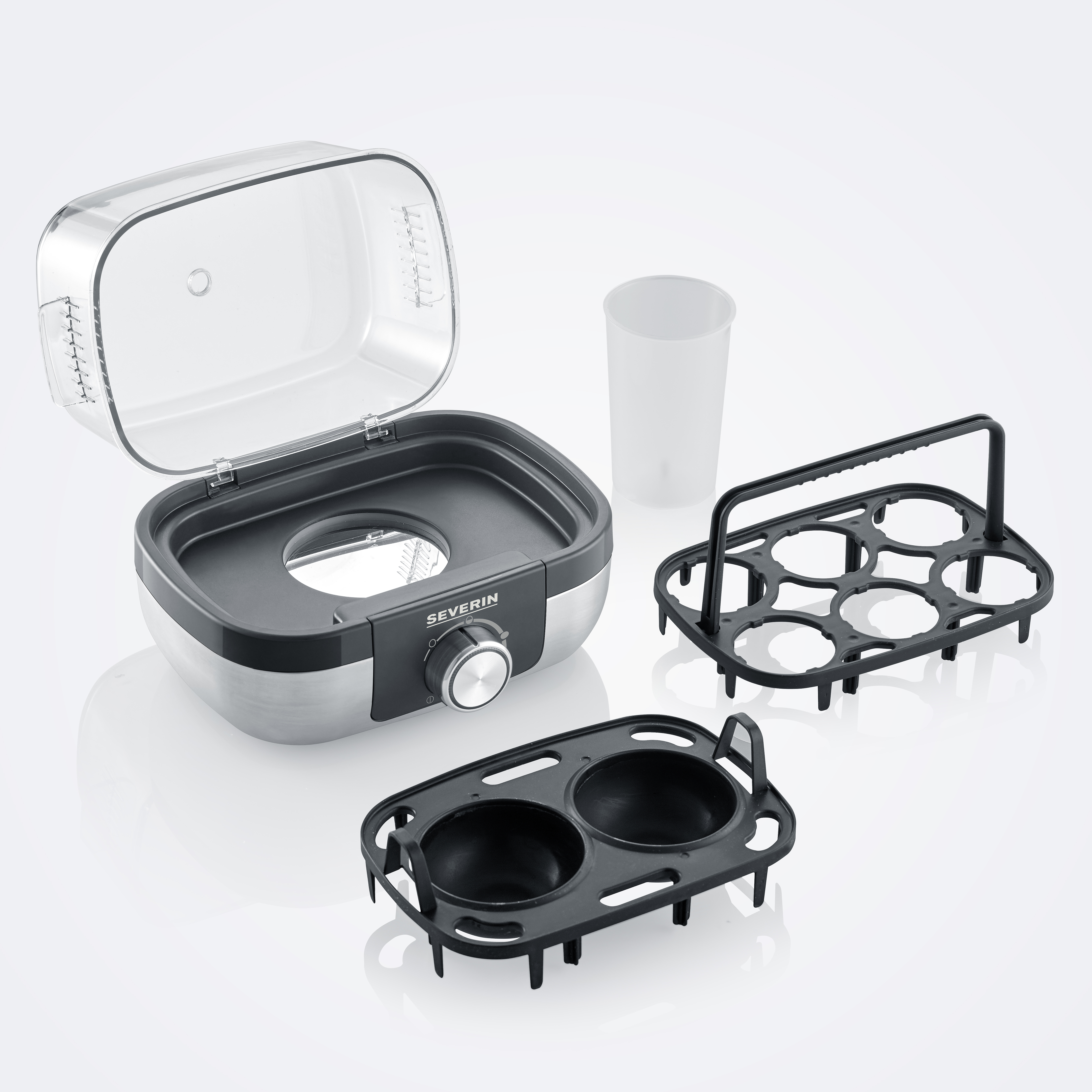 Gotowacz do jajek z akcesoriami. Zawiera uchwyty na jajka, miarkę i przezroczystą pokrywę.