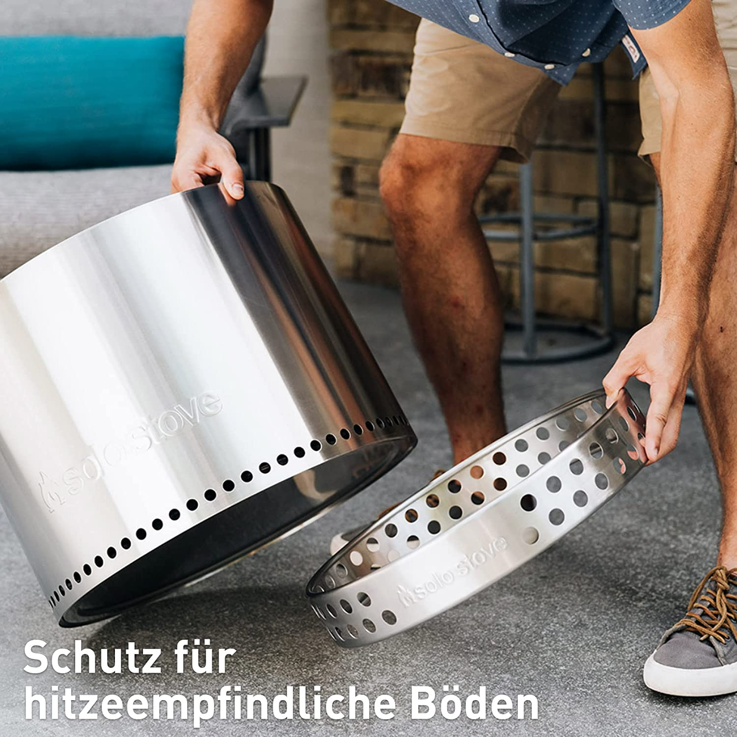 Person hält Feuerstellenkomponente, mit Bodenschutz.