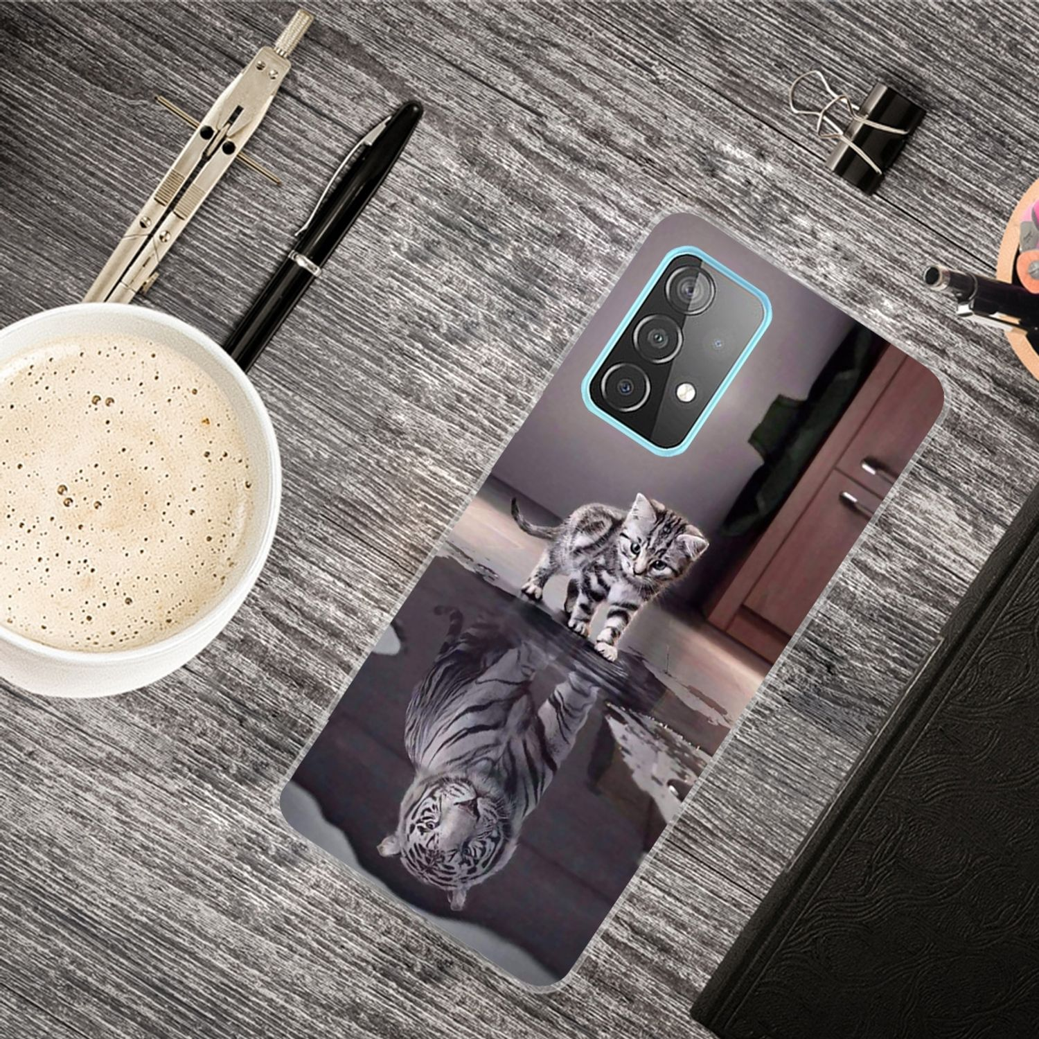 Handyhülle mit einem Kätzchen und Tigerreflexion liegt auf einem Holzschreibtisch mit Kaffee und Stift.