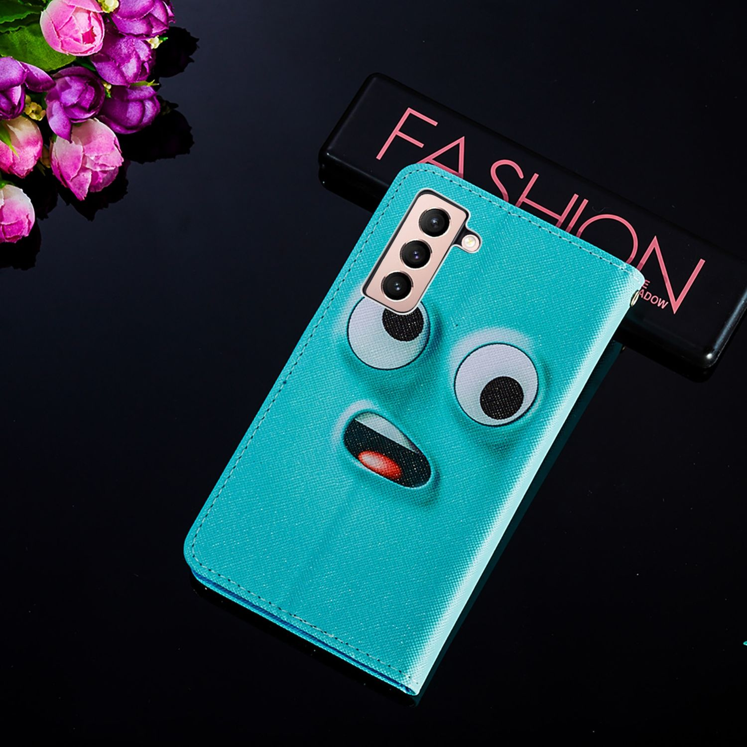 Türkisfarbenes Handycase mit Cartoon-Gesicht. Schwarze glänzende Oberfläche. Make-up-Palette.