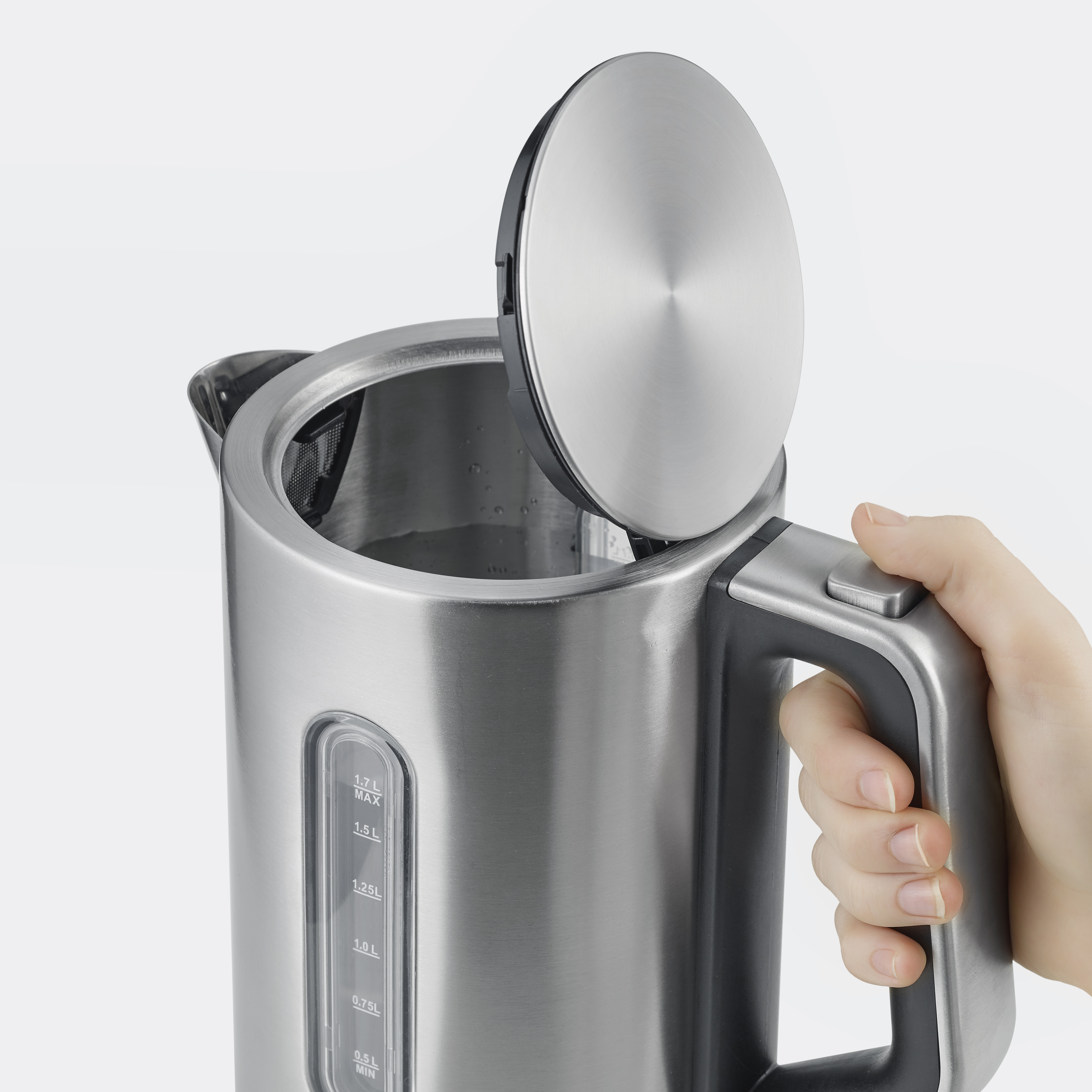 Elektryczny czajnik ze stali nierdzewnej z otwartą pokrywą, dłoń trzymająca uchwyt.