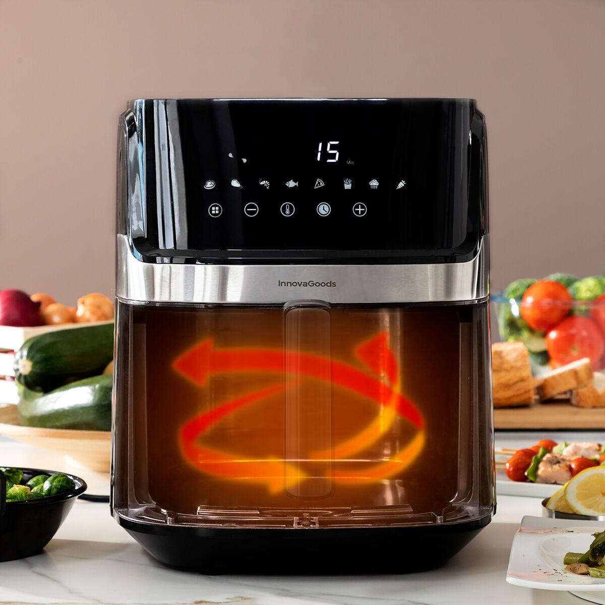 Eine schwarze Heißluftfritteuse mit Digitalanzeige, die 15 Minuten anzeigt, mit Essen im Hintergrund.