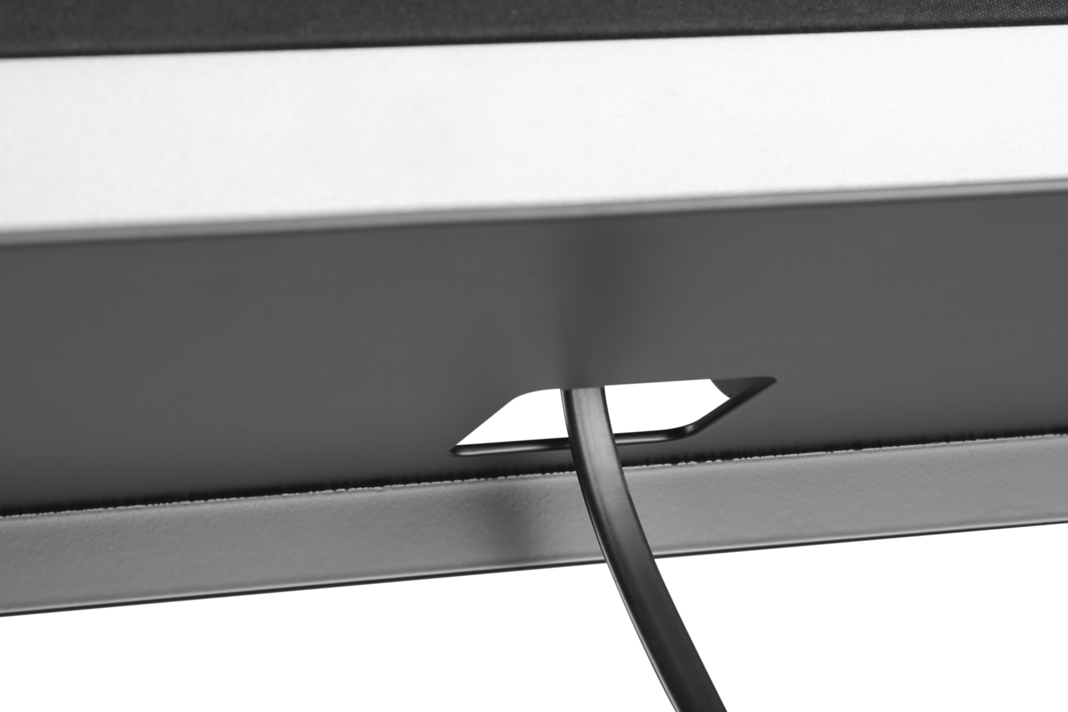 A black cable coming out from the bottom of a dark colored box. White background.