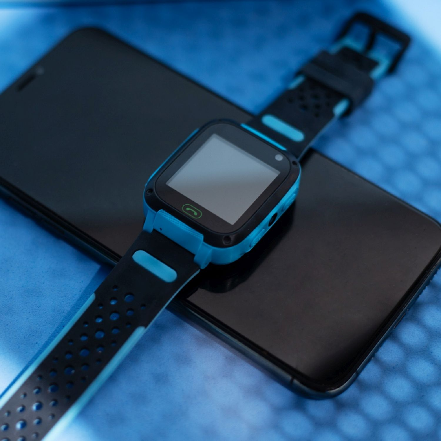 Eine blau-schwarze Smartwatch auf einem schwarzen Smartphone.