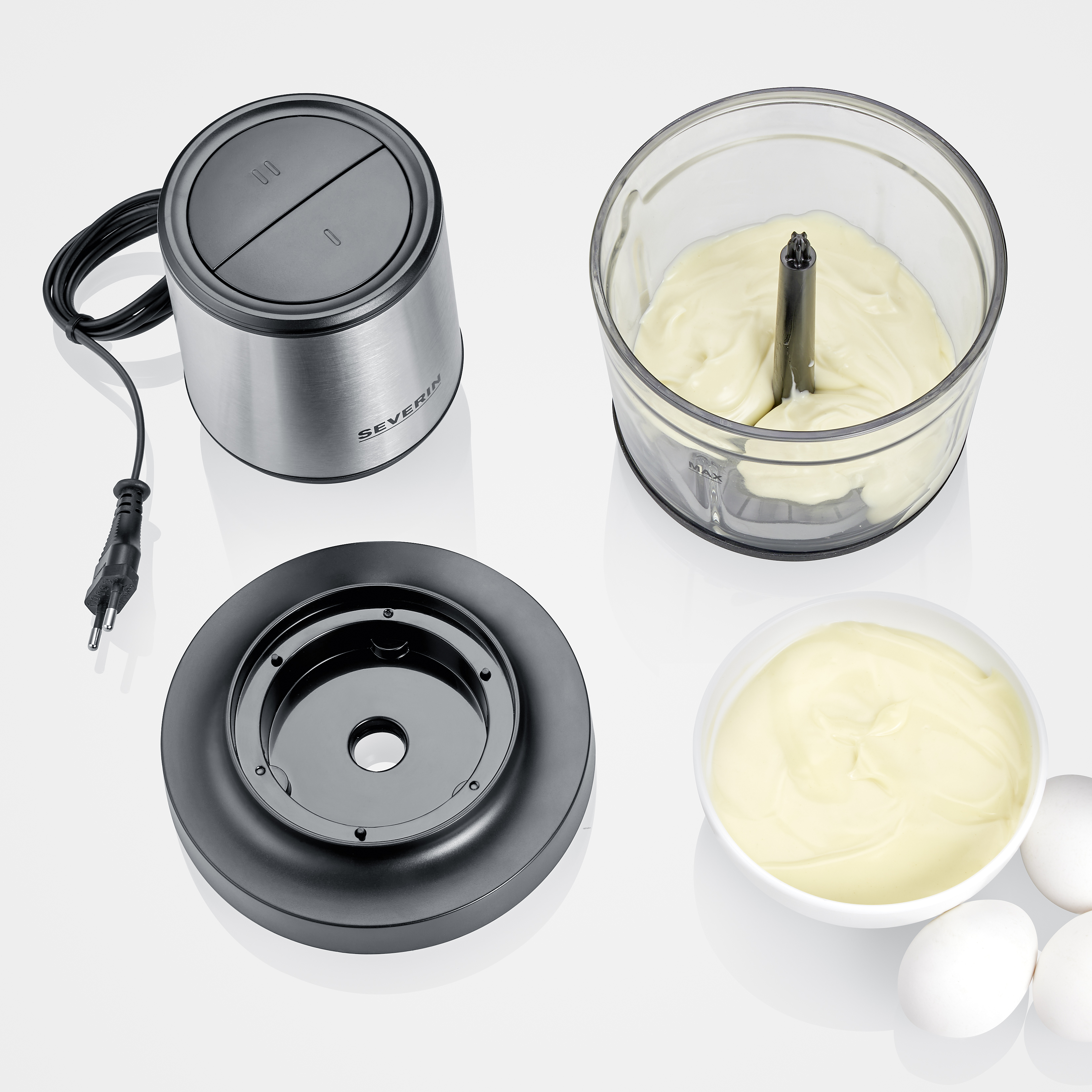 Küchenmaschine mit mehreren Teilen. Das Hauptgerät, die Schüssel mit Essen und ein Deckel sind sichtbar.