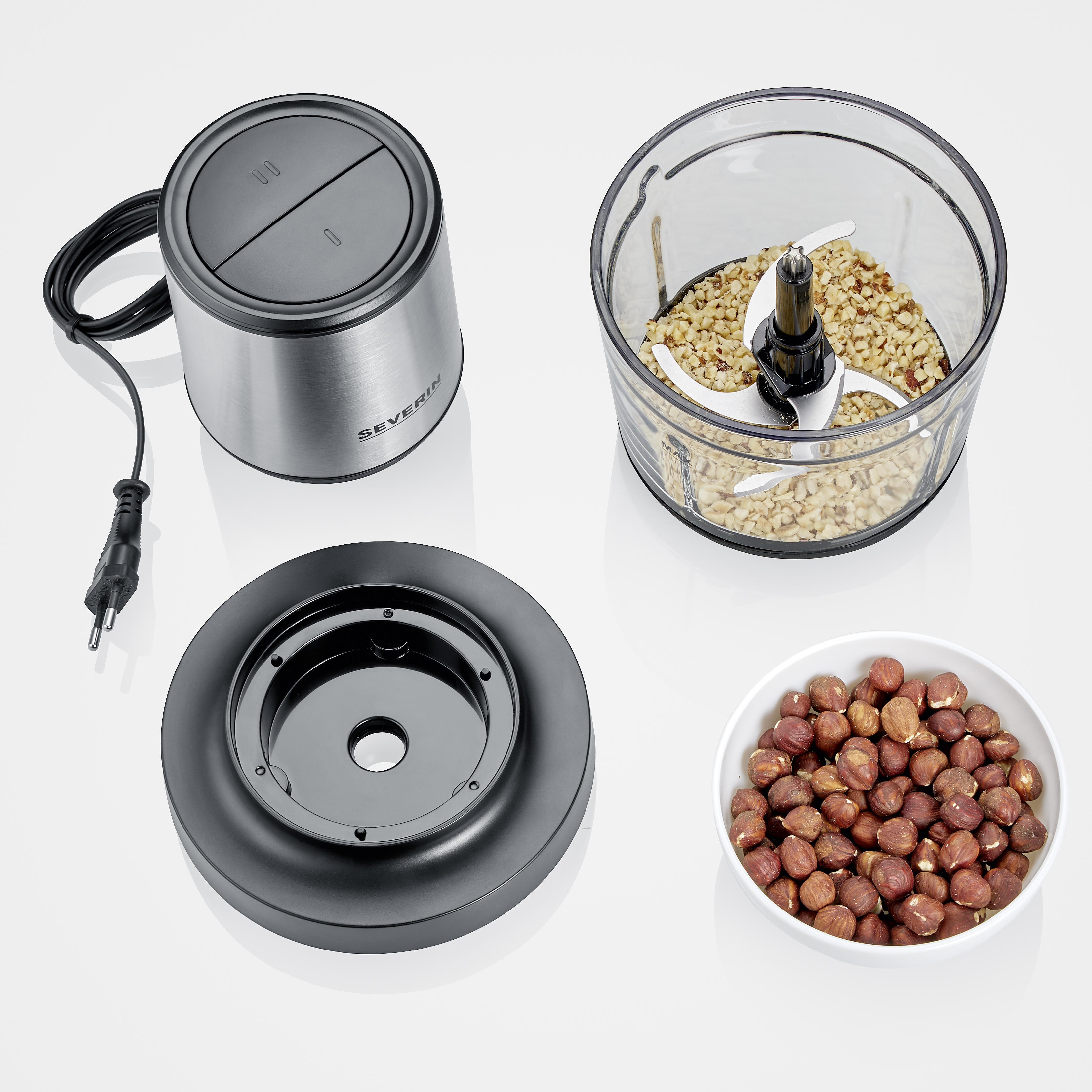 Ein zerlegter Foodprocessor mit einer Schüssel Haselnüssen und einer Schüssel gehackten Nüssen.