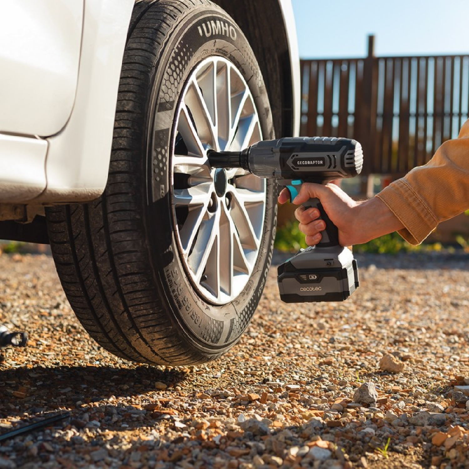 Osoba używająca szarego i czarnego klucza udarowego Cecoraptor do odkręcania opony w samochodzie.