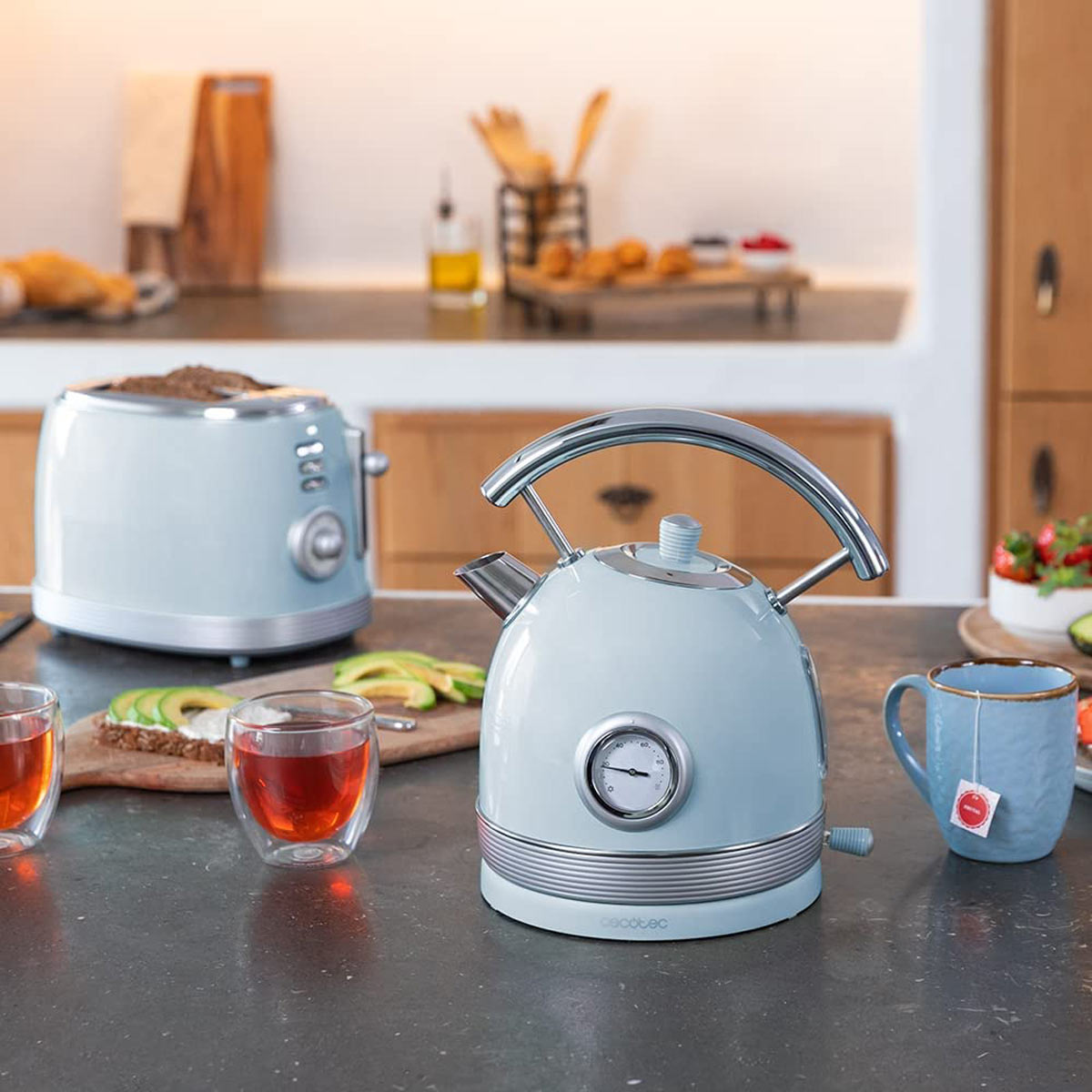 Niebieski czajnik i toster na blacie. Widać też tosty z awokado i herbatę.