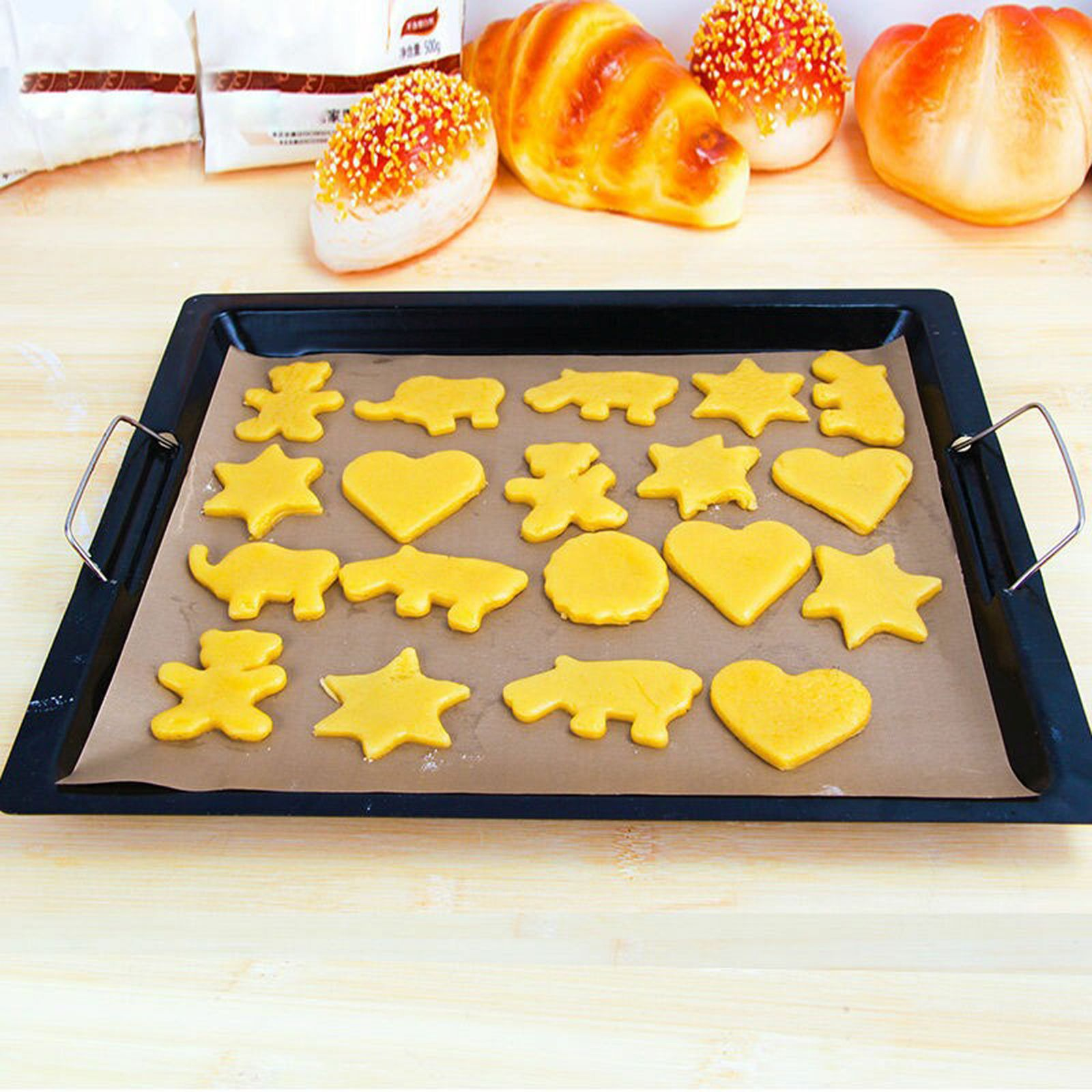Kekse in verschiedenen Formen auf einem Backblech, mit gebackenem Gebäck, auf Holzgrund.