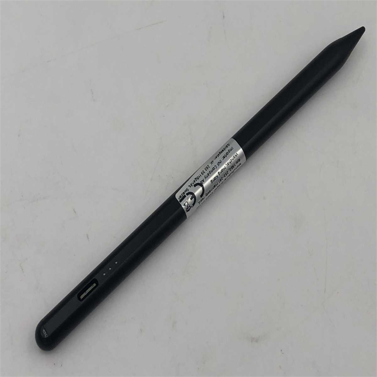 Schwarzer Stift auf weißer Oberfläche. Der Stift ist abgewinkelt und zeigt den Ladeanschluss.