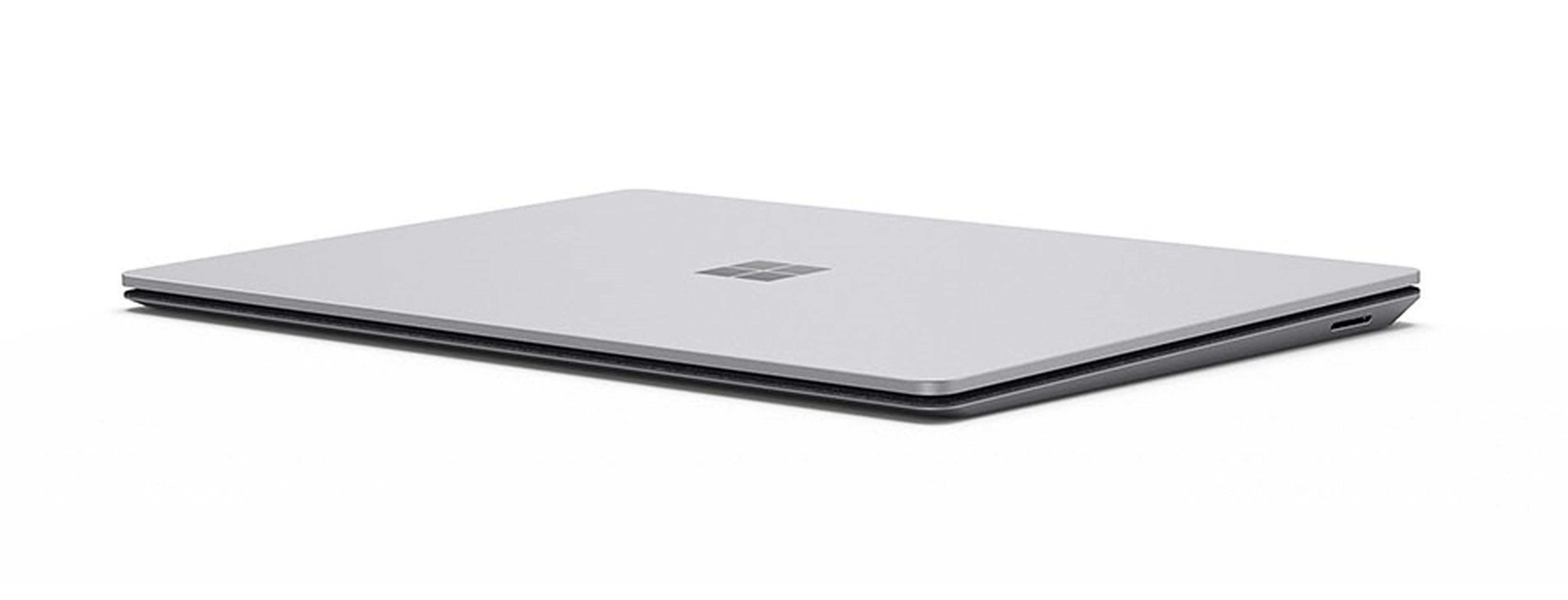 Das Bild zeigt einen geschlossenen silbernen Laptop auf einer weißen Oberfläche. Das Microsoft-Logo ist sichtbar.