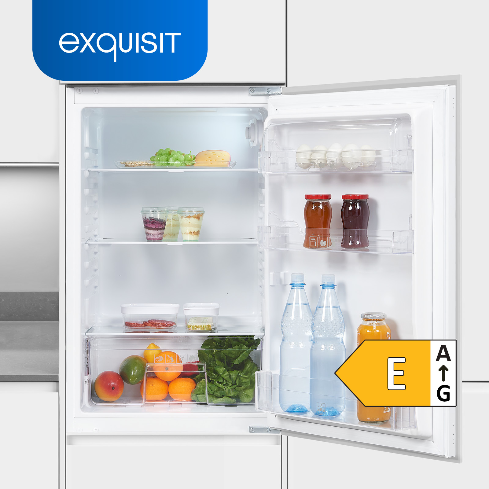 Un frigorífico con la puerta abierta, mostrando estantes con frutas, tarros, botellas y una etiqueta energética.
