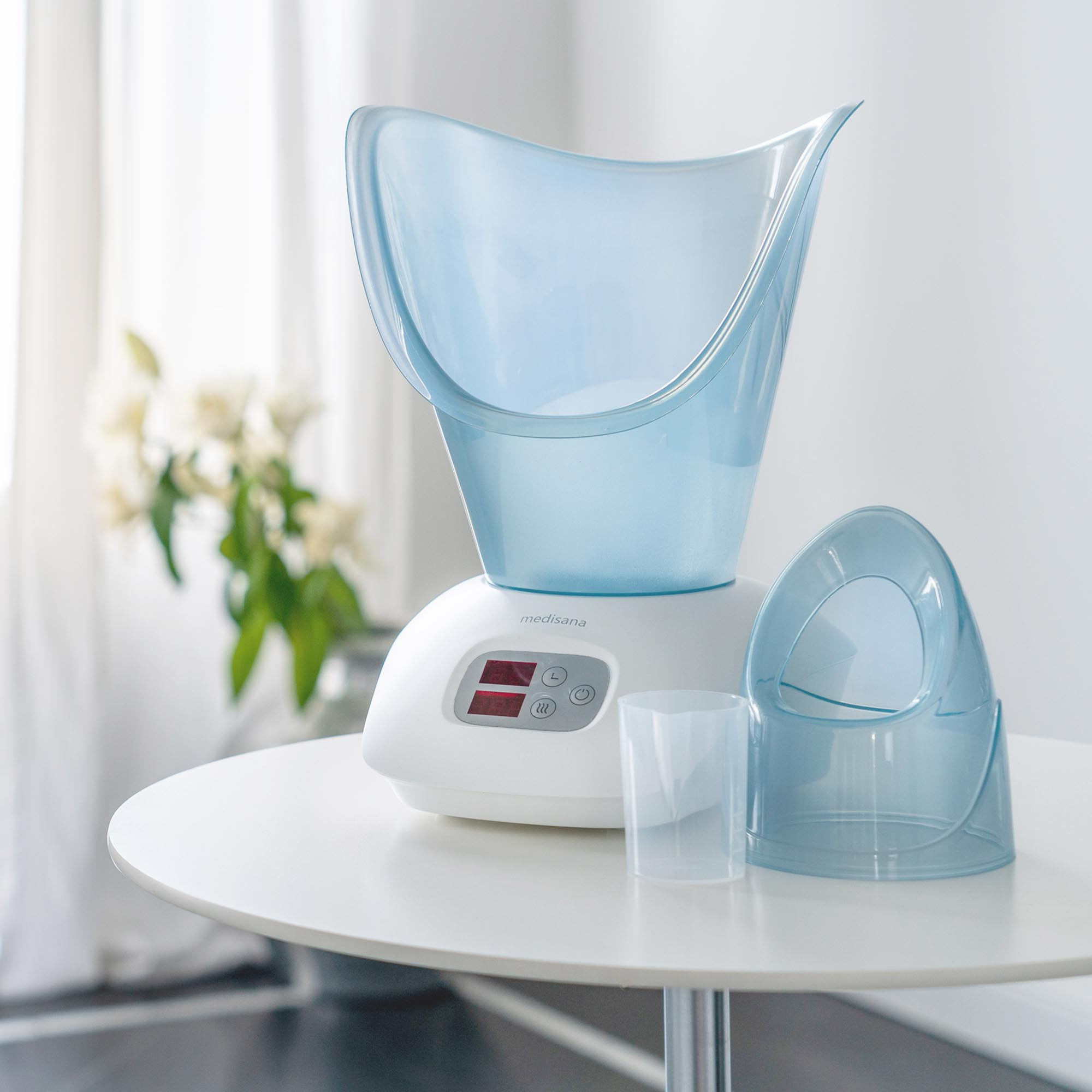 Vapeur faciale blanche et bleue sur une table, avec un vase de fleurs en arrière-plan.
