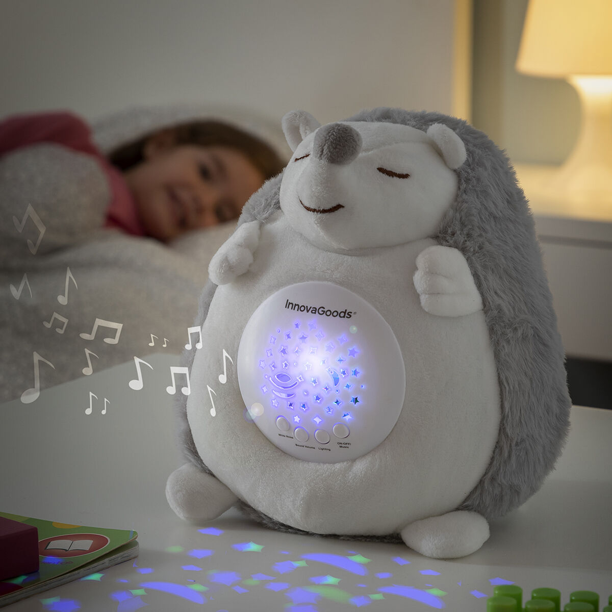 Giocattolo a forma di riccio con luce notturna su un tavolo. Un bambino dorme sullo sfondo.