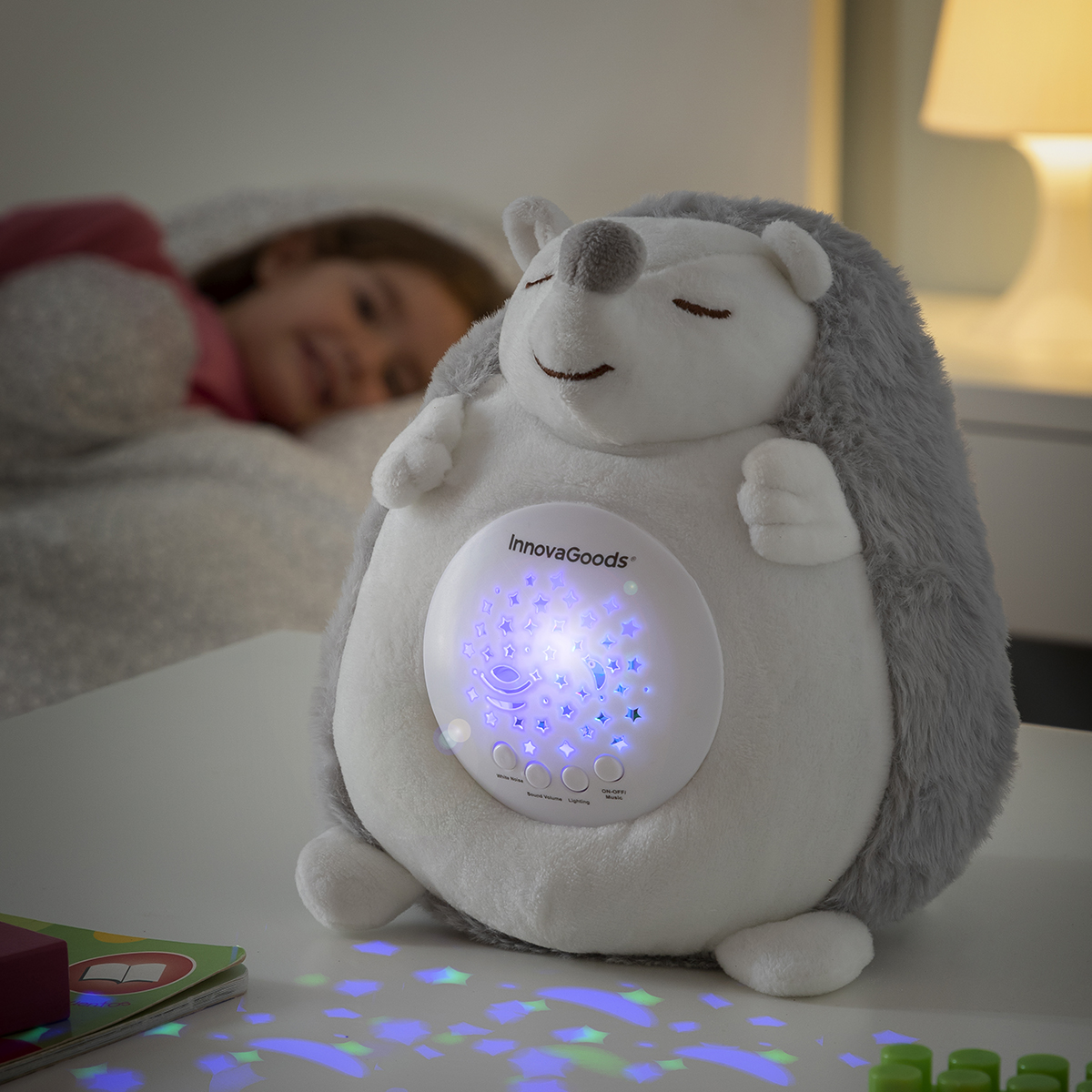 Un bambino dorme accanto a una luce notturna a forma di riccio che proietta stelle.