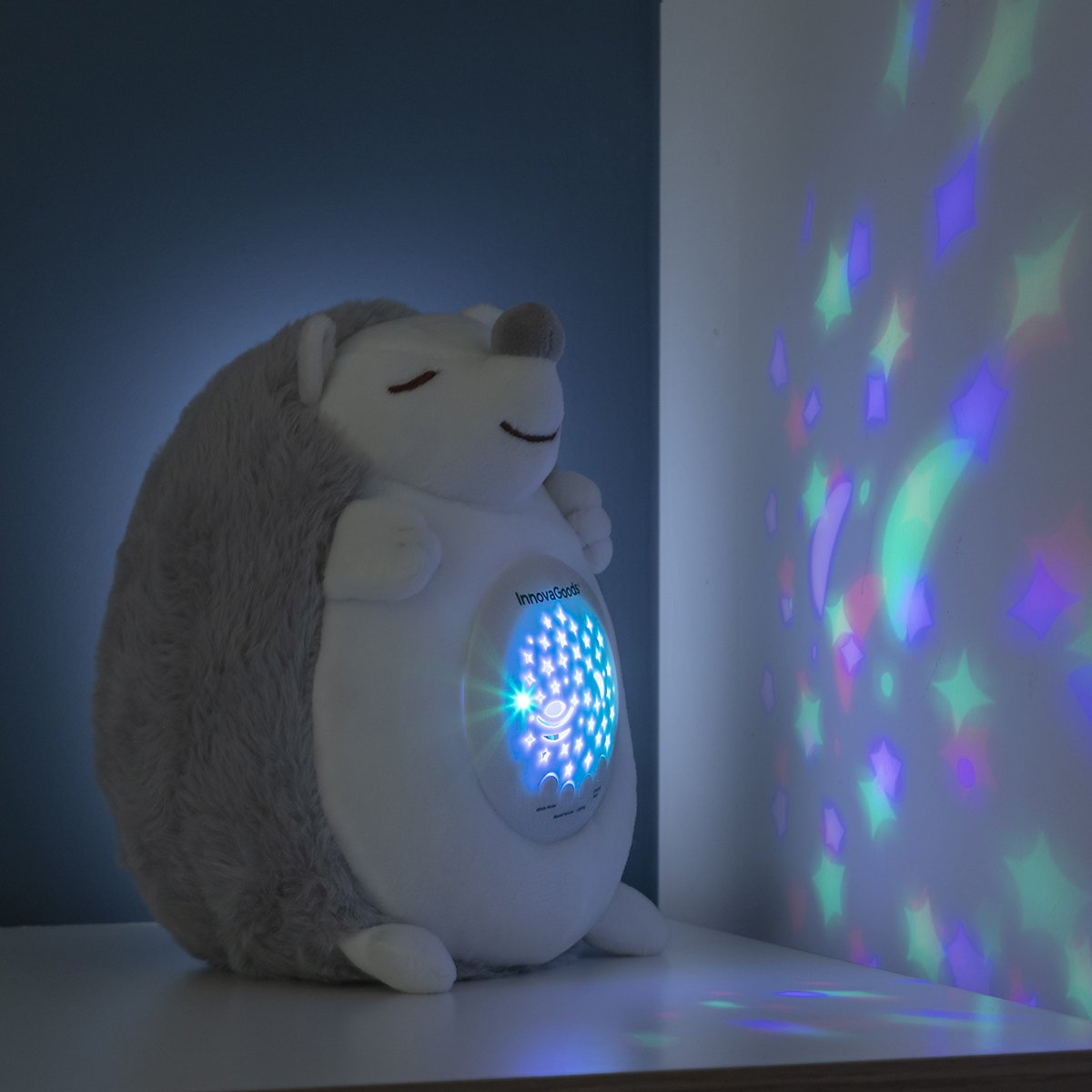 Luce notturna a forma di riccio con proiezione di stelle su un muro. La luce è su una mensola.