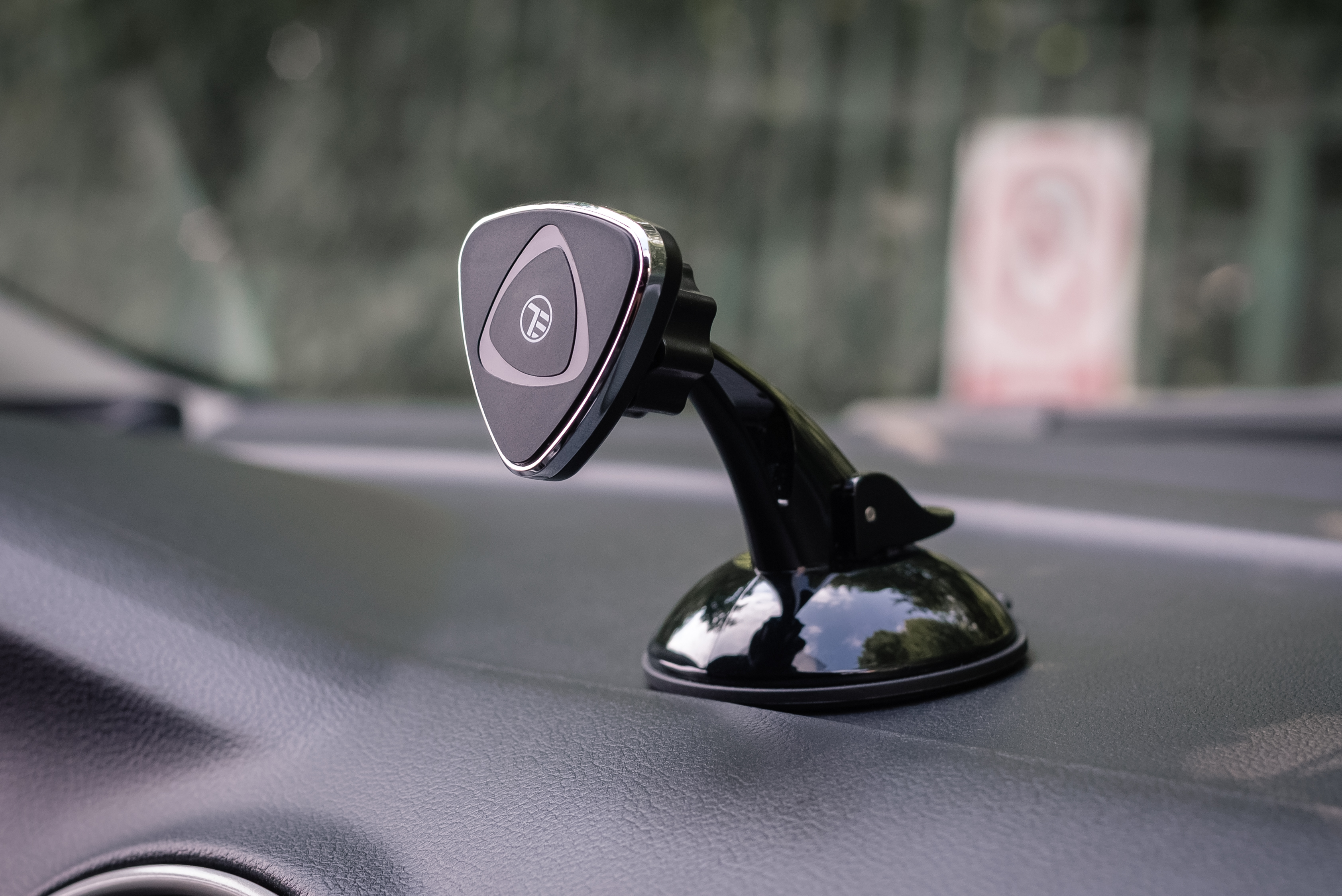 Deska rozdzielcza samochodu z czarnym magnetycznym uchwytem na telefon. Tło jest lekko rozmyte.