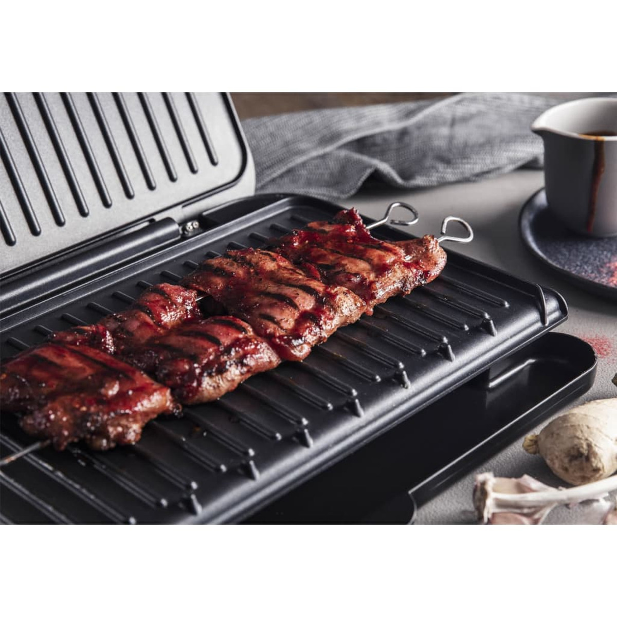 Gegrilltes Fleisch auf einem Grill. Fleisch ist rot und auf Spießen. Grill ist schwarz.