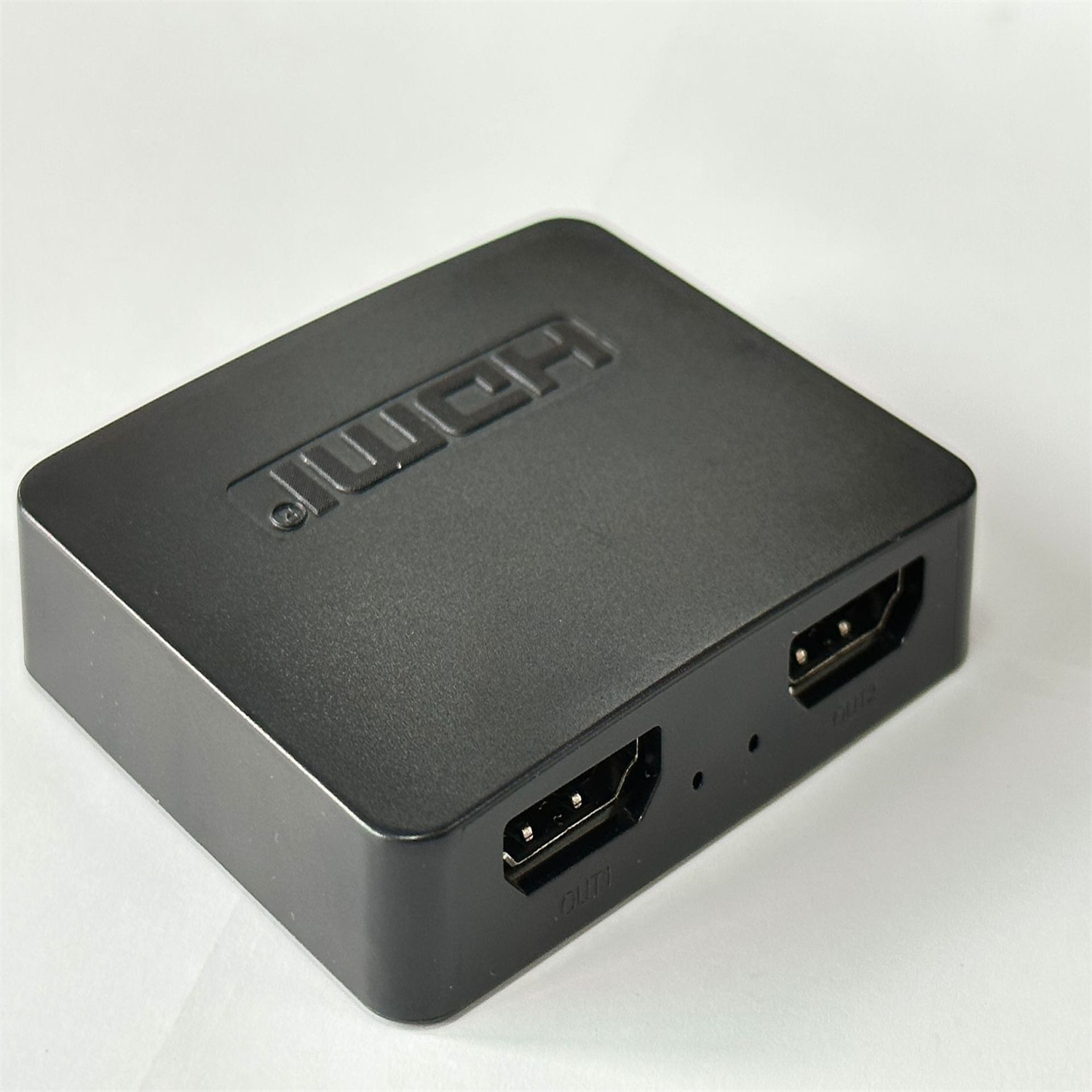 Czarny rozdzielacz HDMI z dwoma portami HDMI i portem zasilania, na białym tle.