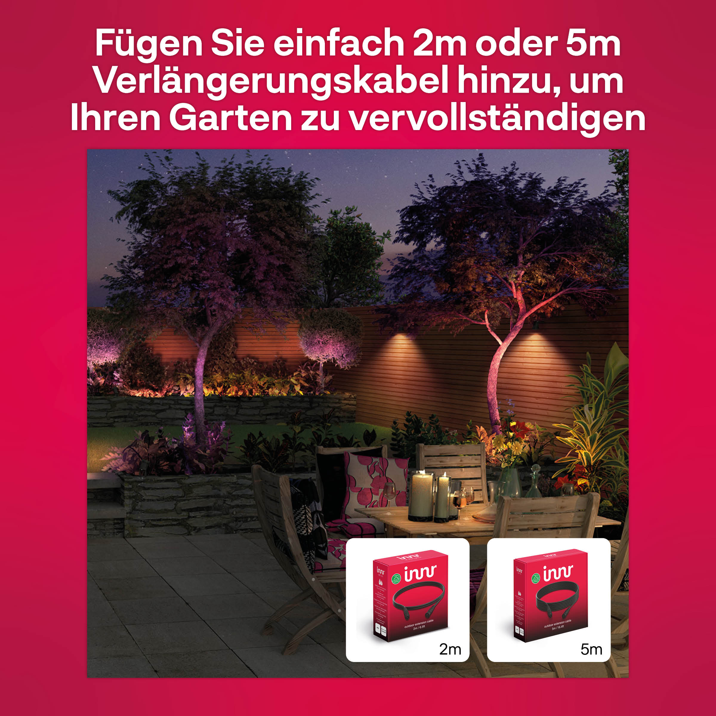 A garden scene at night with illuminated trees and a table with candles and boxes of outdoor lights.