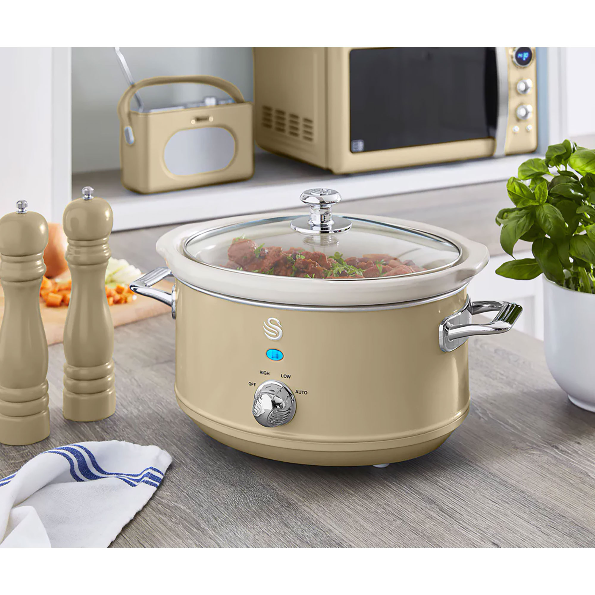 Beiger Slow Cooker mit Glasdeckel, Radio, Mikrowelle, Kräutern und Salz-/Pfefferstreuer.