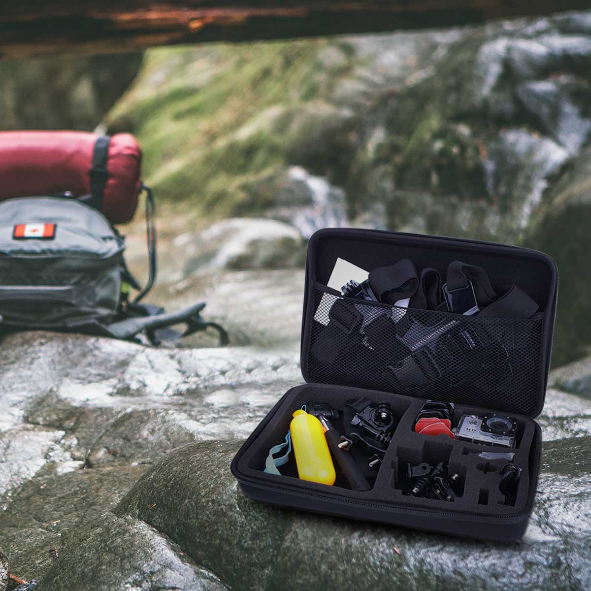 Geöffnete schwarze Tasche mit Action-Kamera-Zubehör, auf Felsen am Wasser.